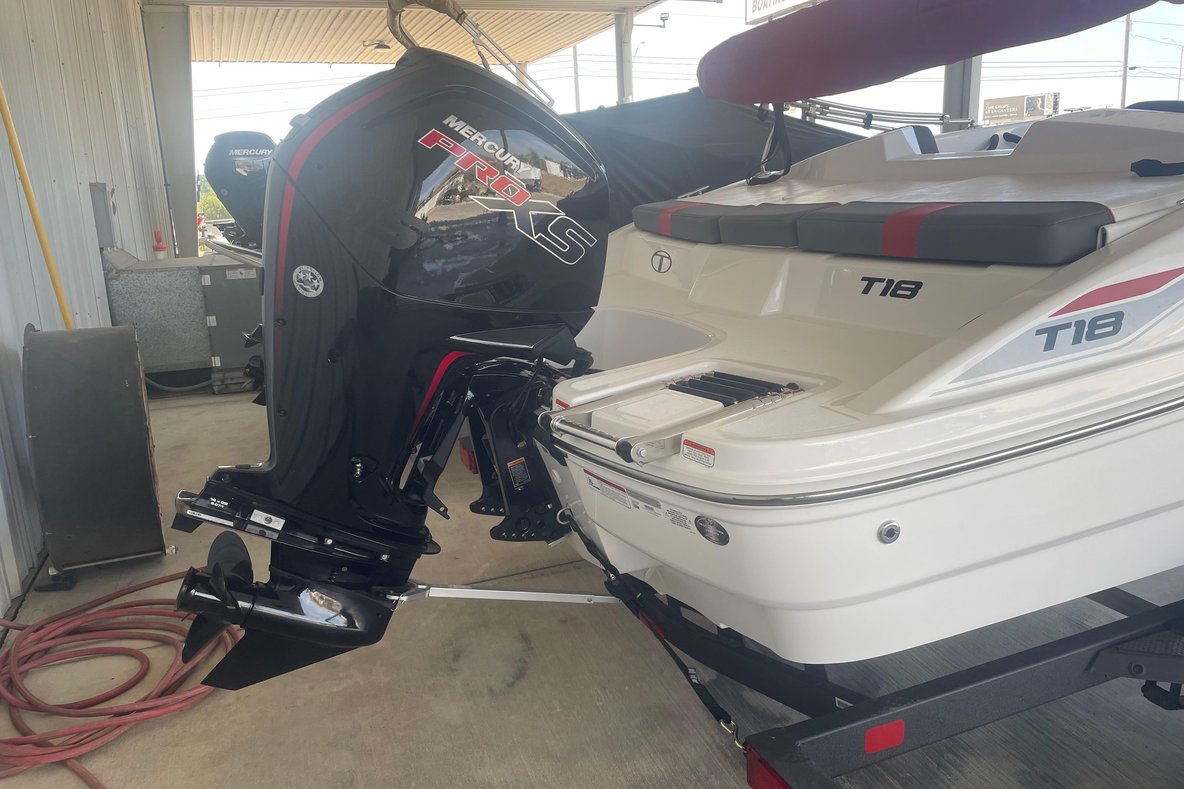 2026 Tahoe T18 boat with Mercury Pro XS outboard motor in a covered area.