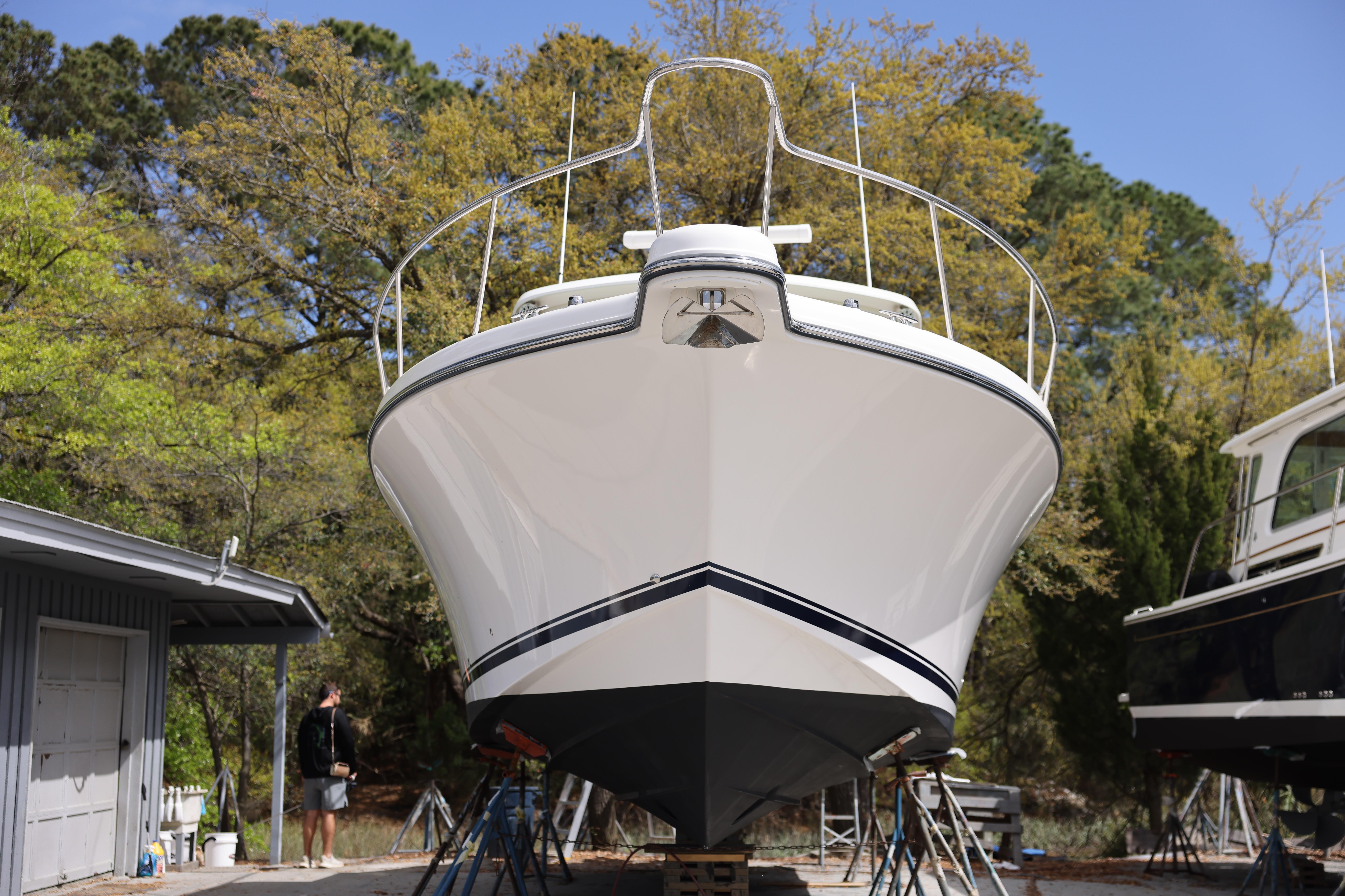 2015 Pursuit OS 385 Offshore boat on stands, surrounded by trees and buildings.
