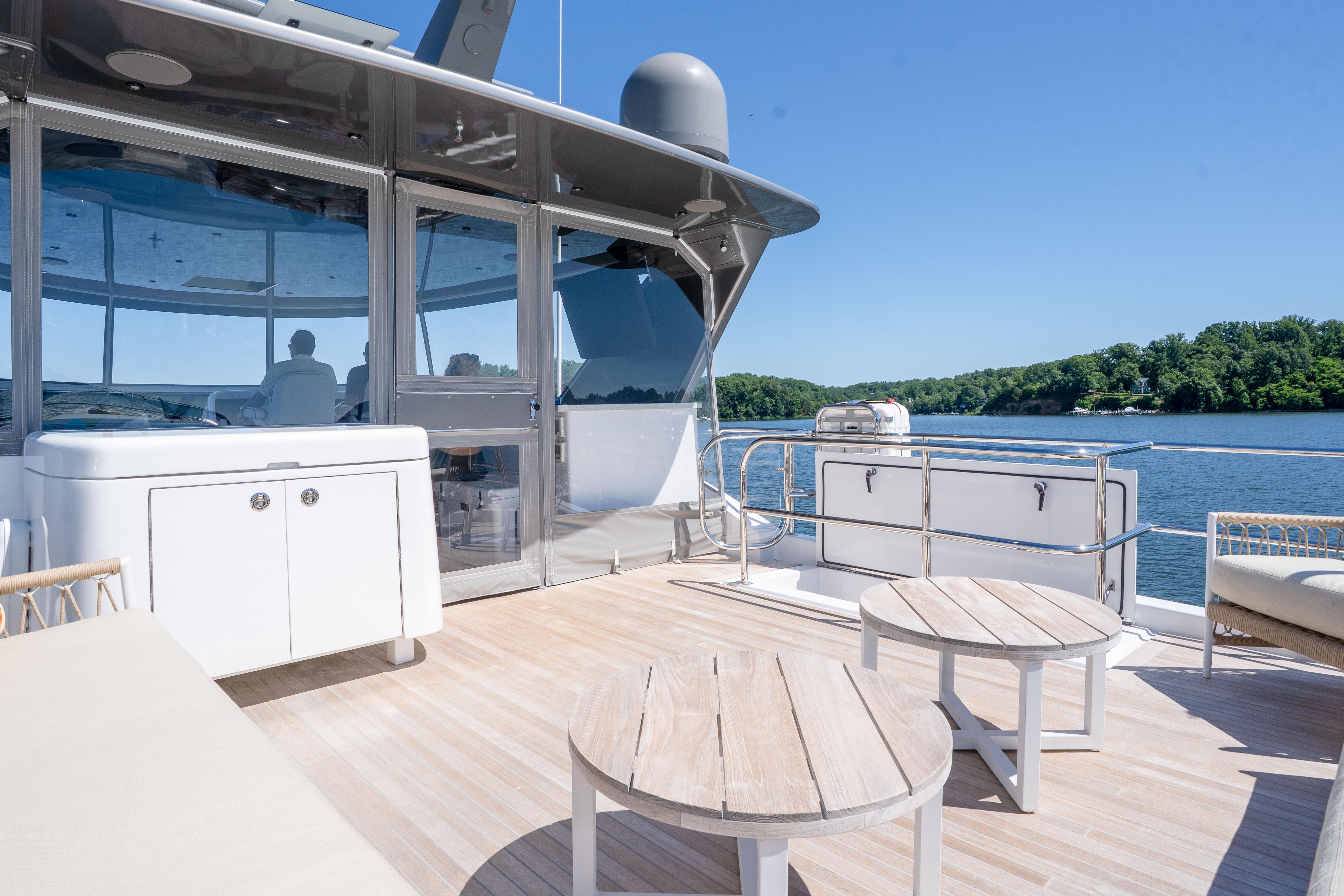 Luxurious 2021 Hatteras M75 Panacera yacht deck with seating, overlooking serene water and lush greenery.
