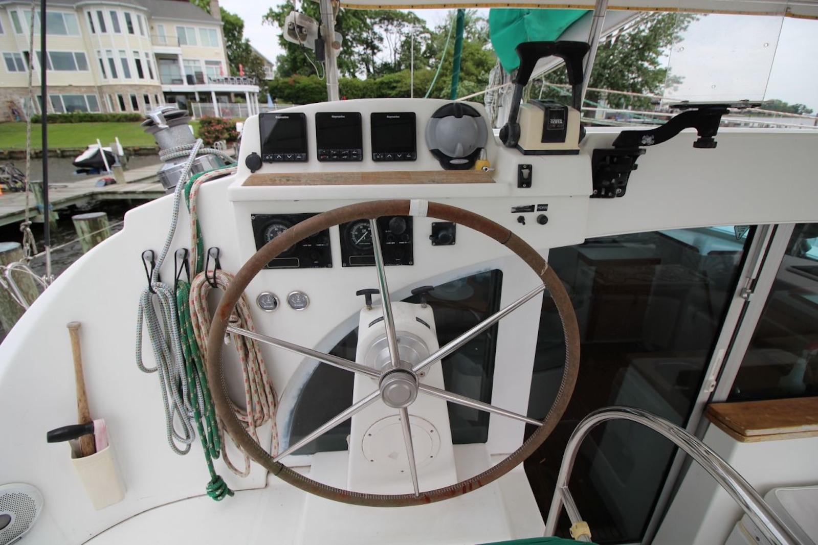 Steering wheel and controls of a 2004 Lagoon 380 catamaran at a marina.