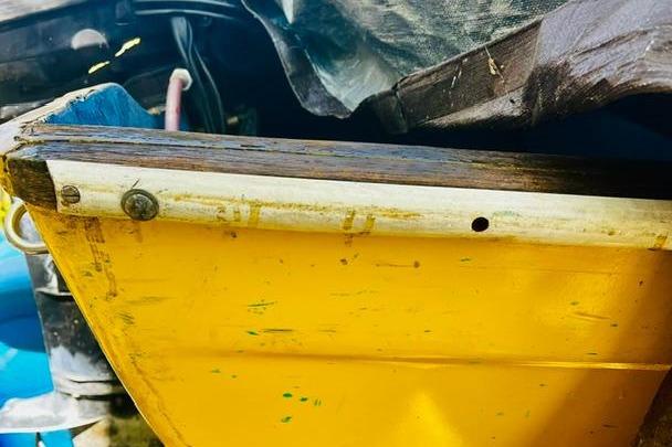 Yellow hull of a vintage 1968 John Dory Center Console boat, partially covered.