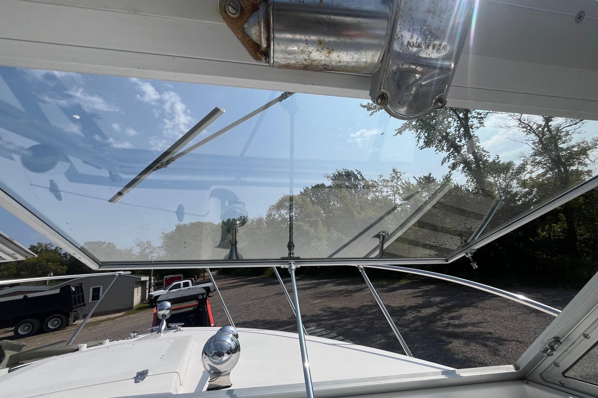 1975 Bertram 26 Moppie boat windshield view with clear sky and trees.