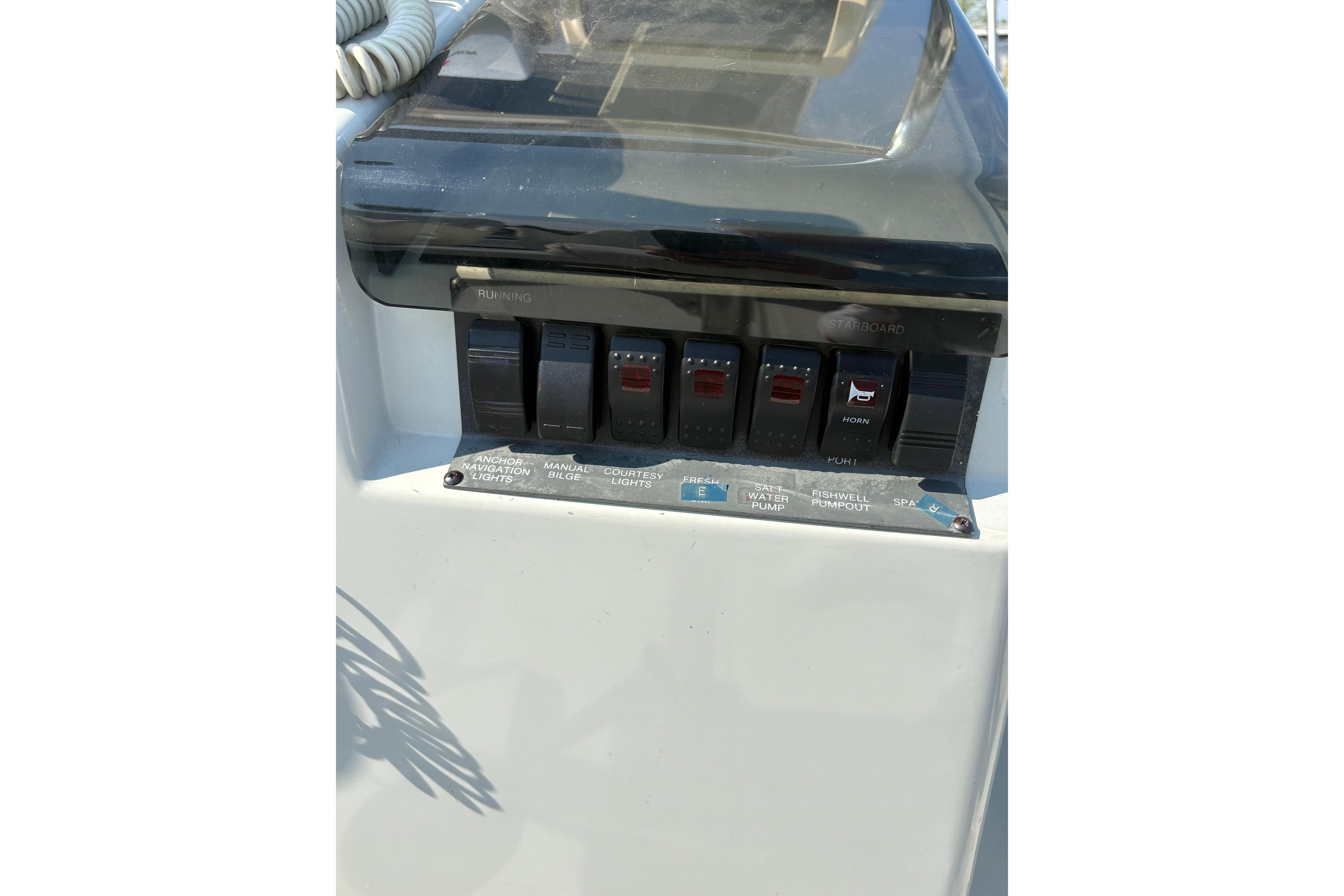 Control panel of a 1993 Boston Whaler 21 Outrage boat with labeled switches.