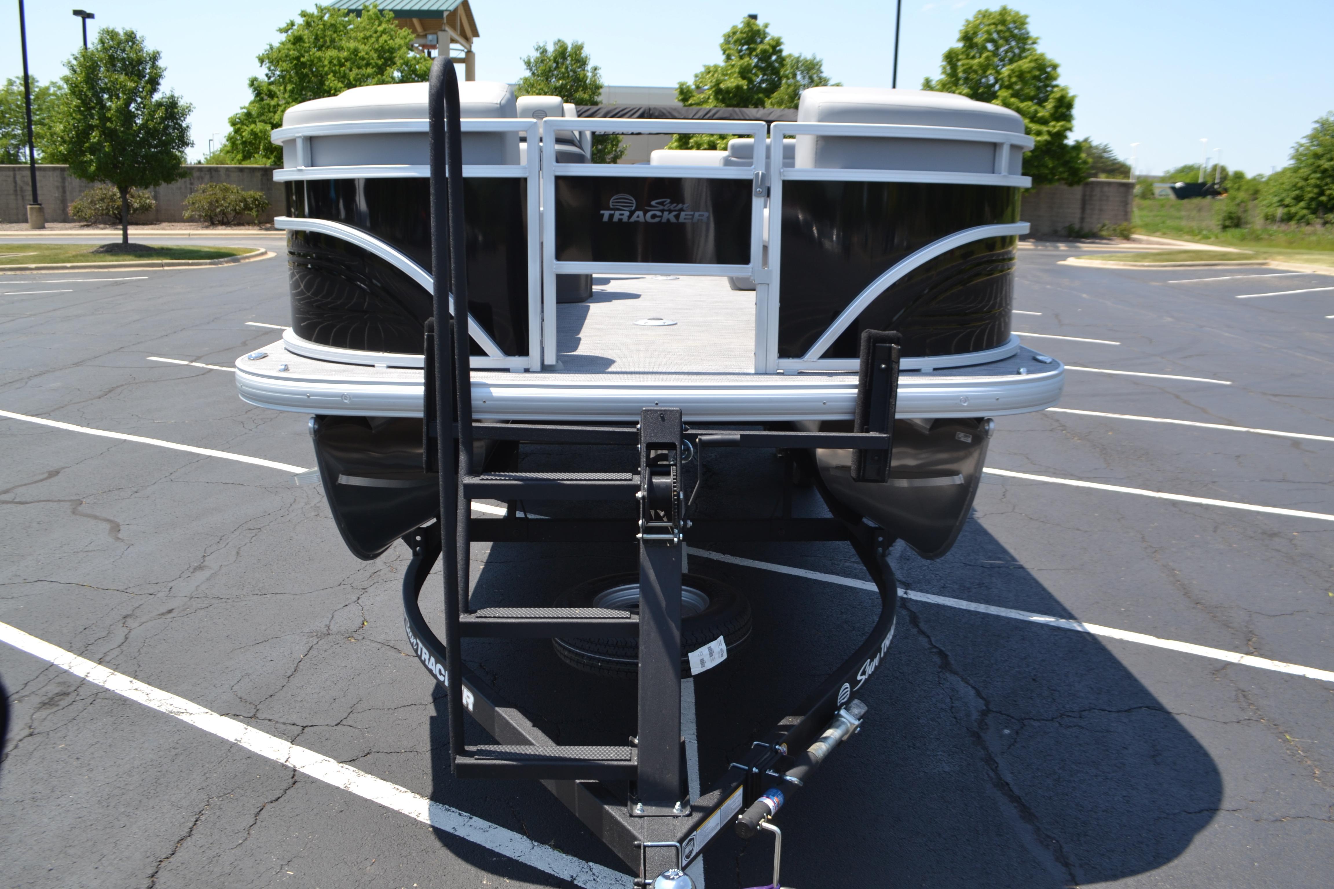 2026 Sun Tracker SportFish 22 DLX pontoon boat on trailer in parking lot.