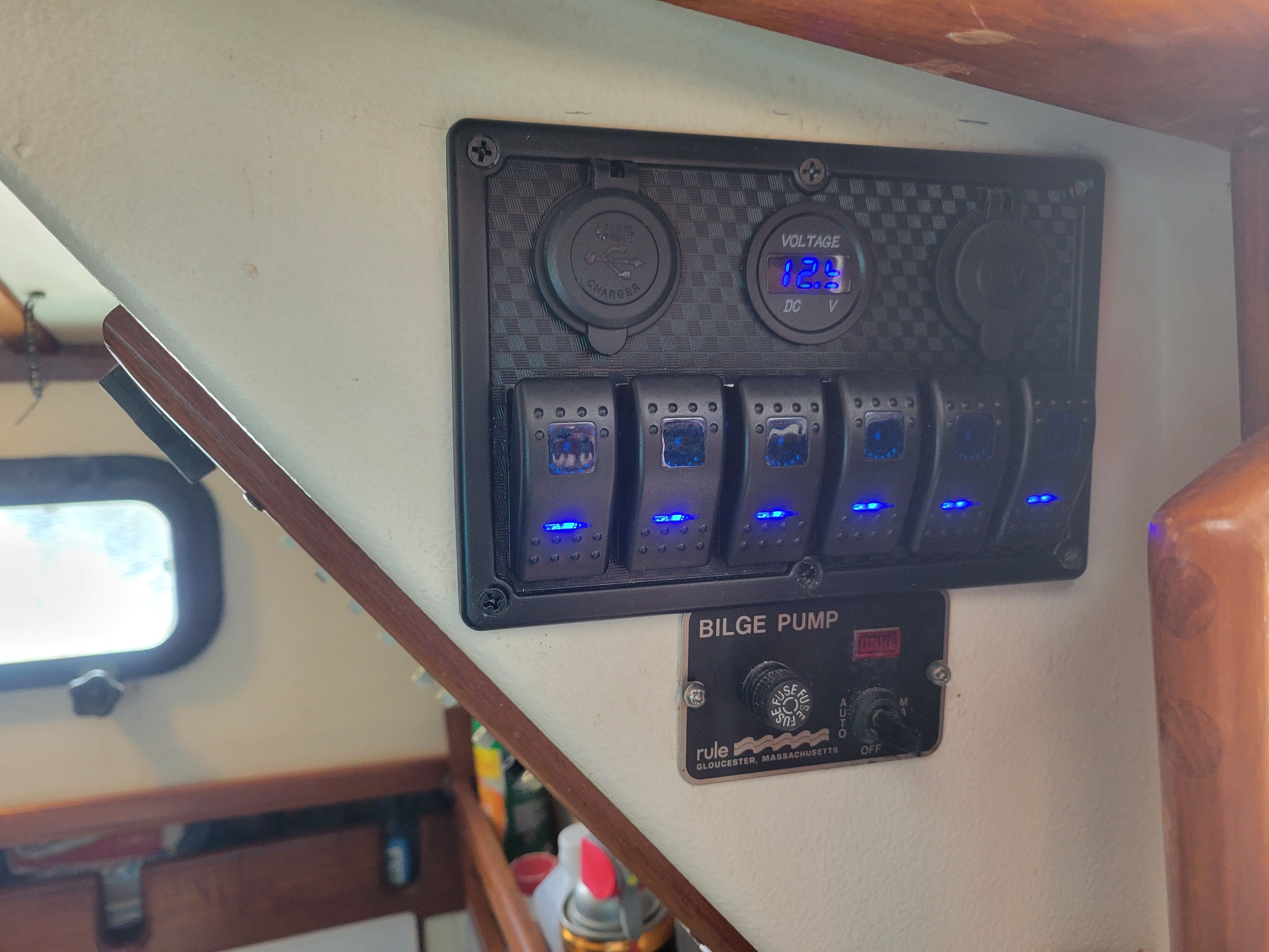 Electrical switch panel with voltage display and bilge pump switch inside a boat.