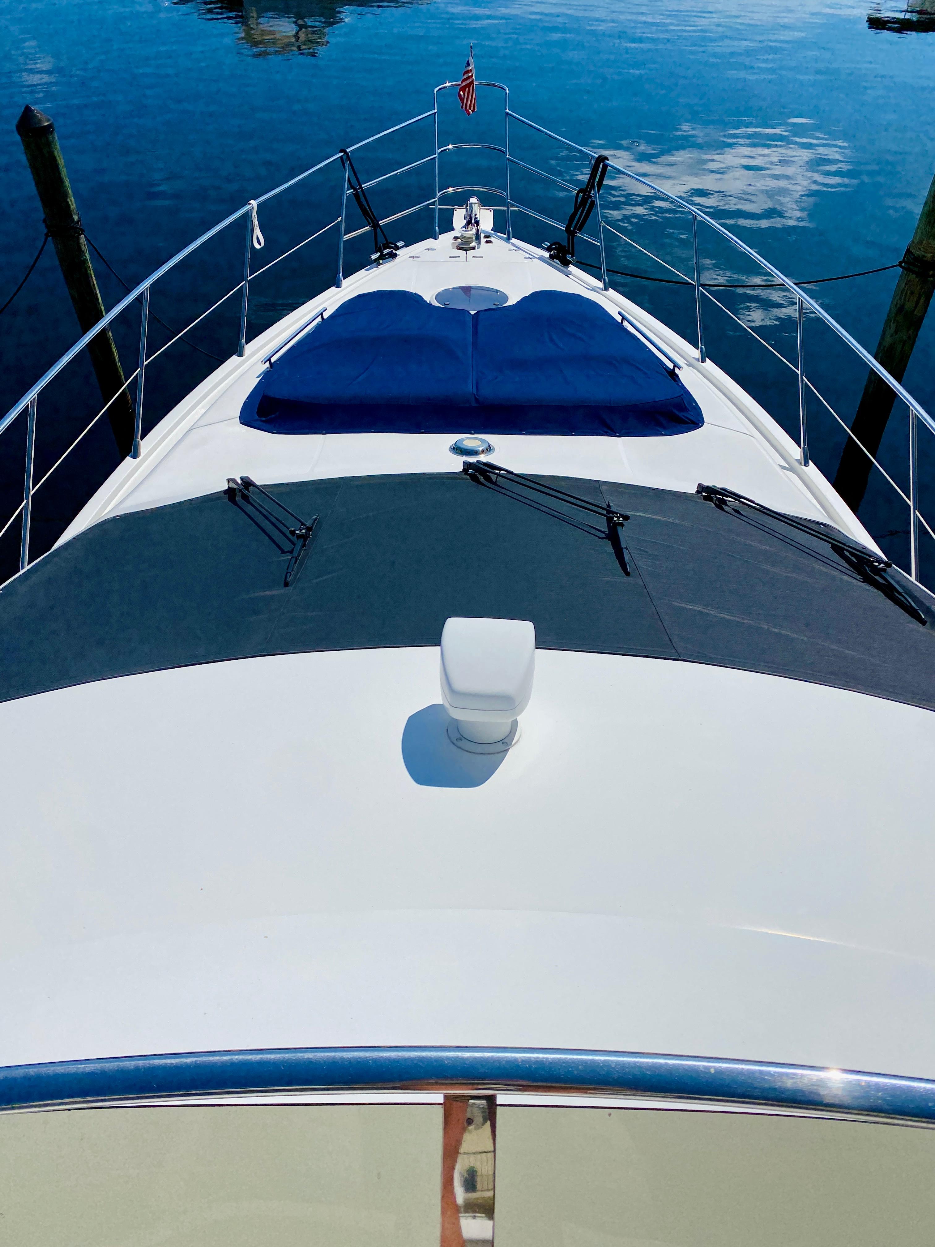 Azimut 55 yacht, 2002 model, docked with blue cushions on deck, reflecting on calm water.