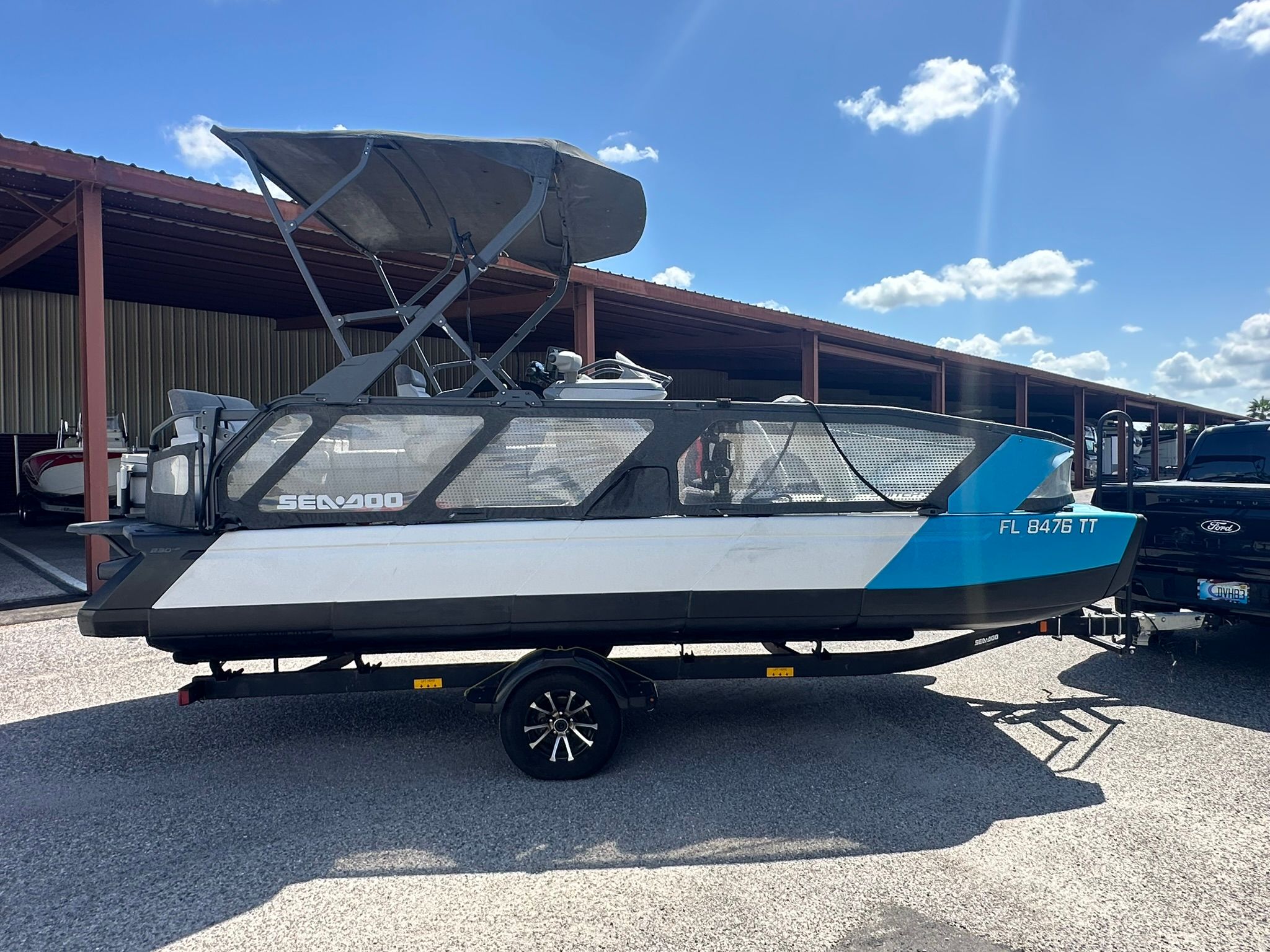 A 2023 Sea-Doo 21 SWITCH SPORT boat on a trailer, parked under a covered area.