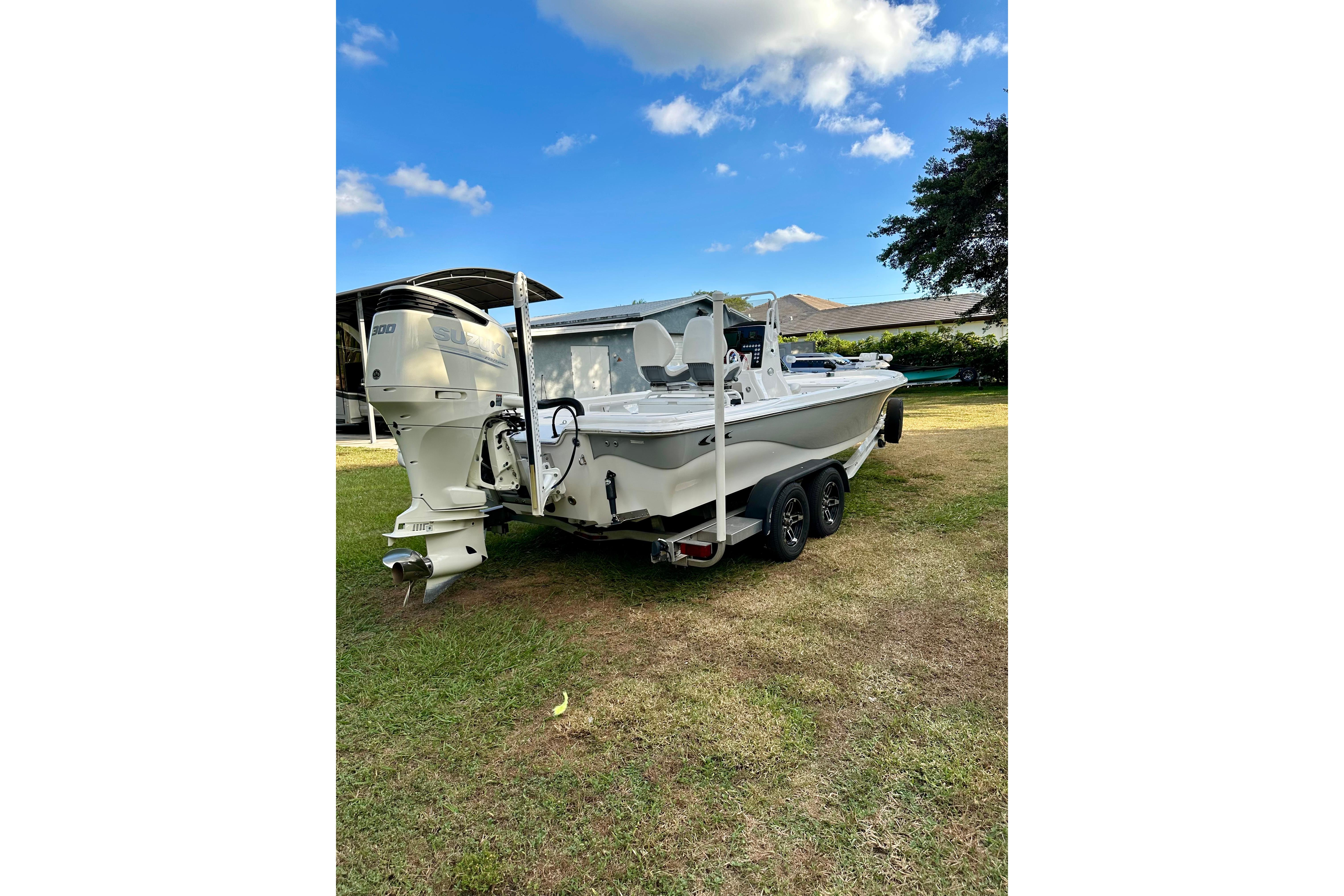 2017 Blue Wave 2400 PureBay boat on trailer, parked on grass under blue sky.