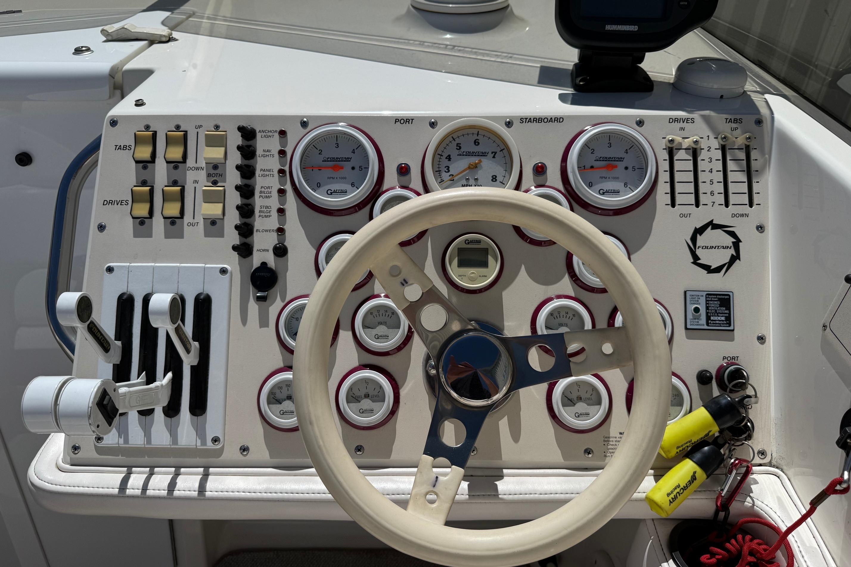 Control panel of a 1998 Fountain 35 Lightning boat with gauges and steering wheel.