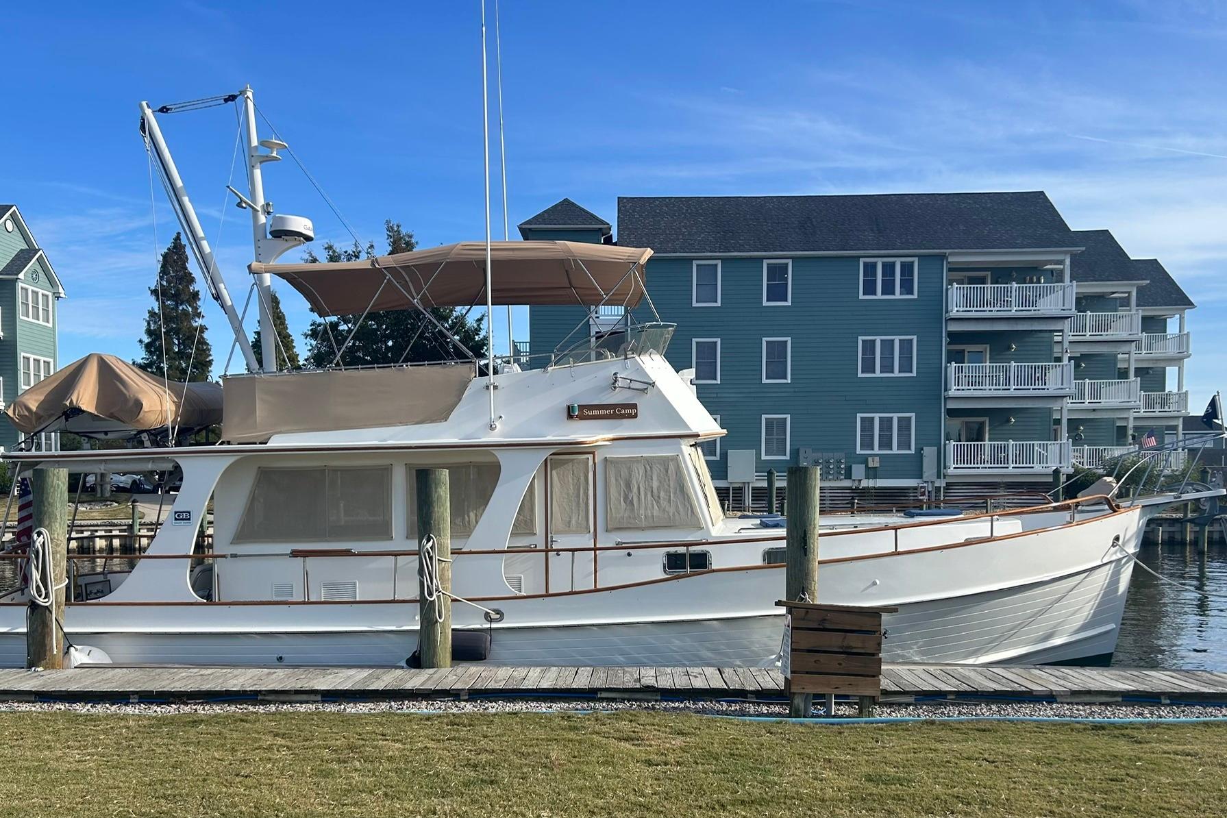 1999 Grand Banks 42 Europa yacht docked near waterfront buildings under clear blue sky.