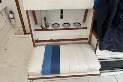 1989 Sea Ray 300 Sundancer boat seat with cup holders and blue-striped cushion.