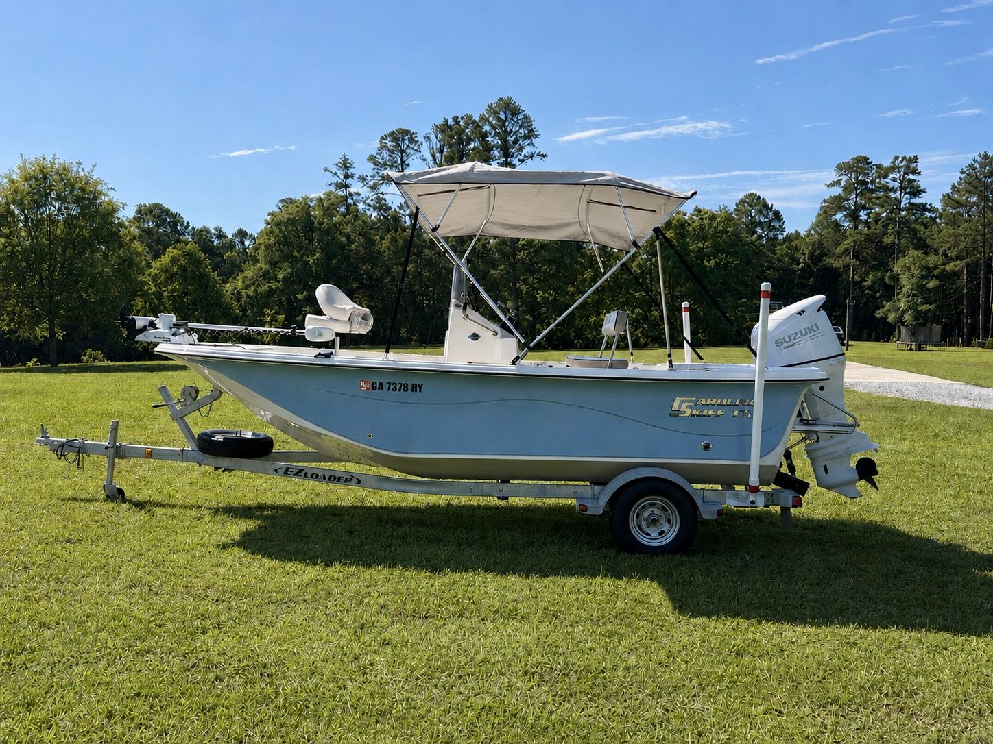 A 2022 Carolina Skiff 17 LS boat on a trailer, set on a grassy field.