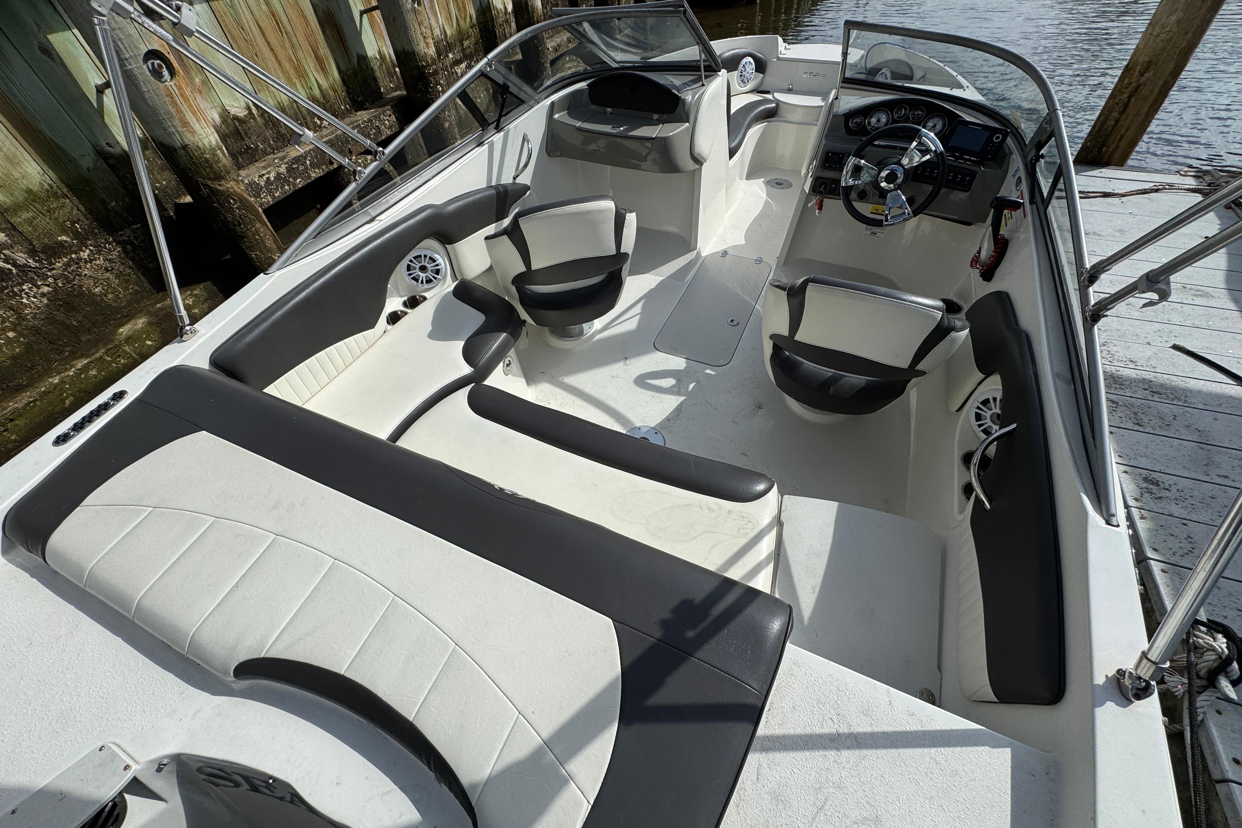 2019 Stingray 204 LR boat interior with seating and steering wheel, docked by wooden posts.