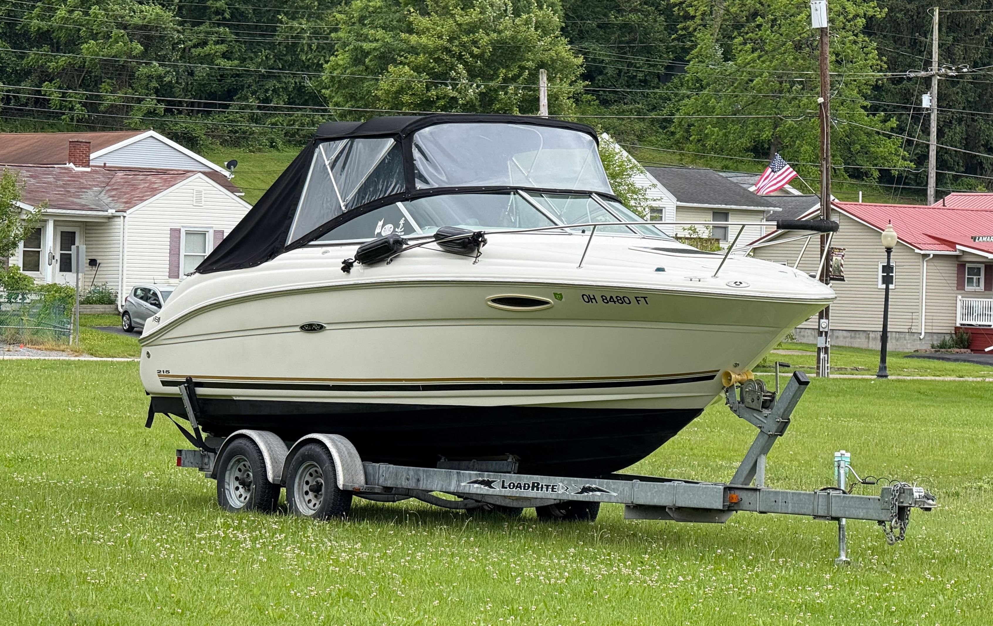 2006 Sea Ray 215 Weekender on trailer in grassy area.