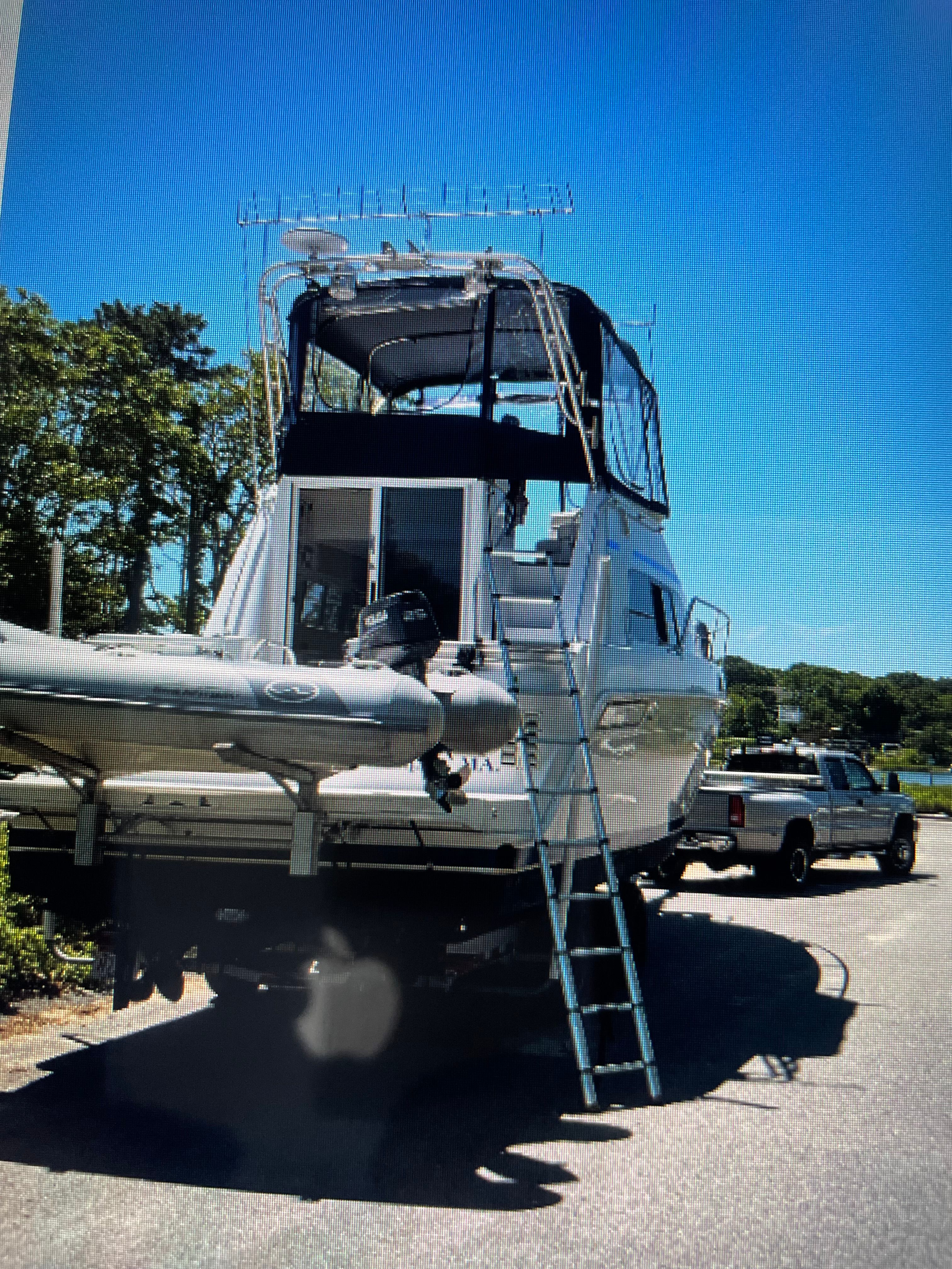 A 1998 Mainship 31 Sedan Bridge on a trailer with a ladder and an inflatable boat.