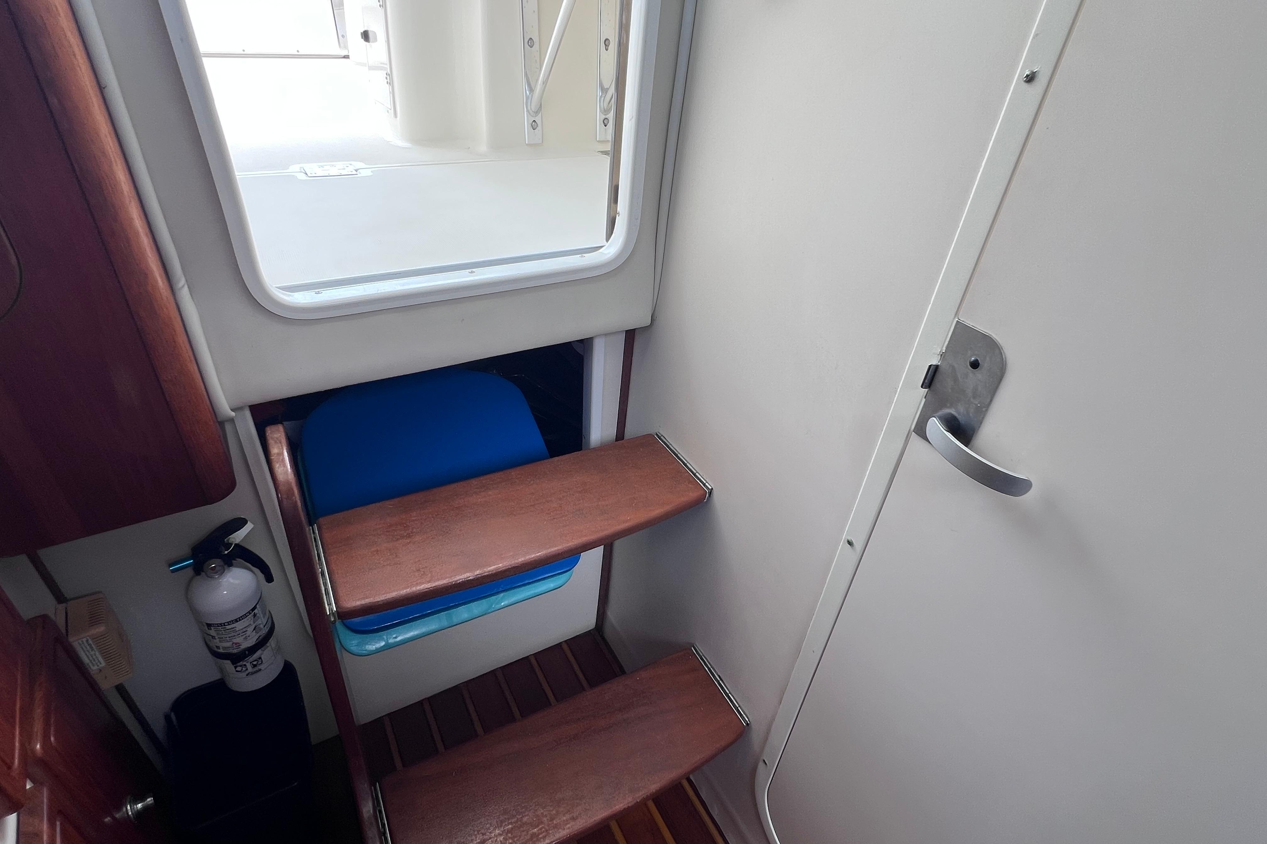 Interior of 2005 Pursuit 3070 Offshore boat with wooden steps and fire extinguisher.