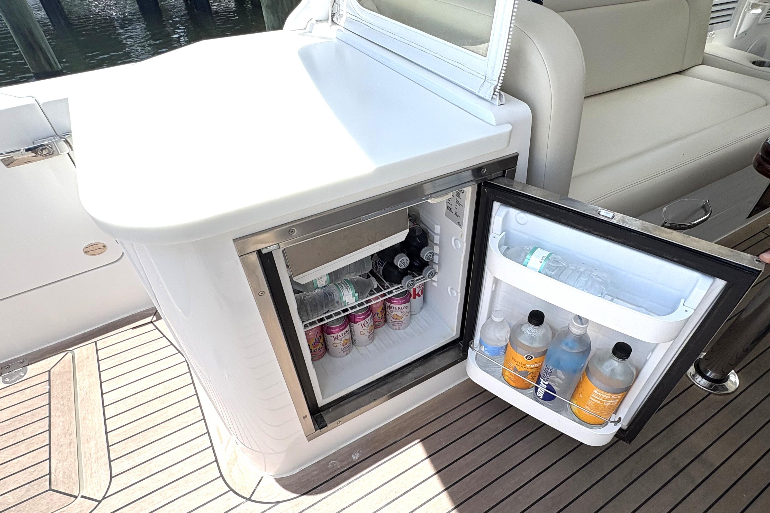 Open mini fridge on 2024 MJM 35z boat, stocked with beverages on deck.