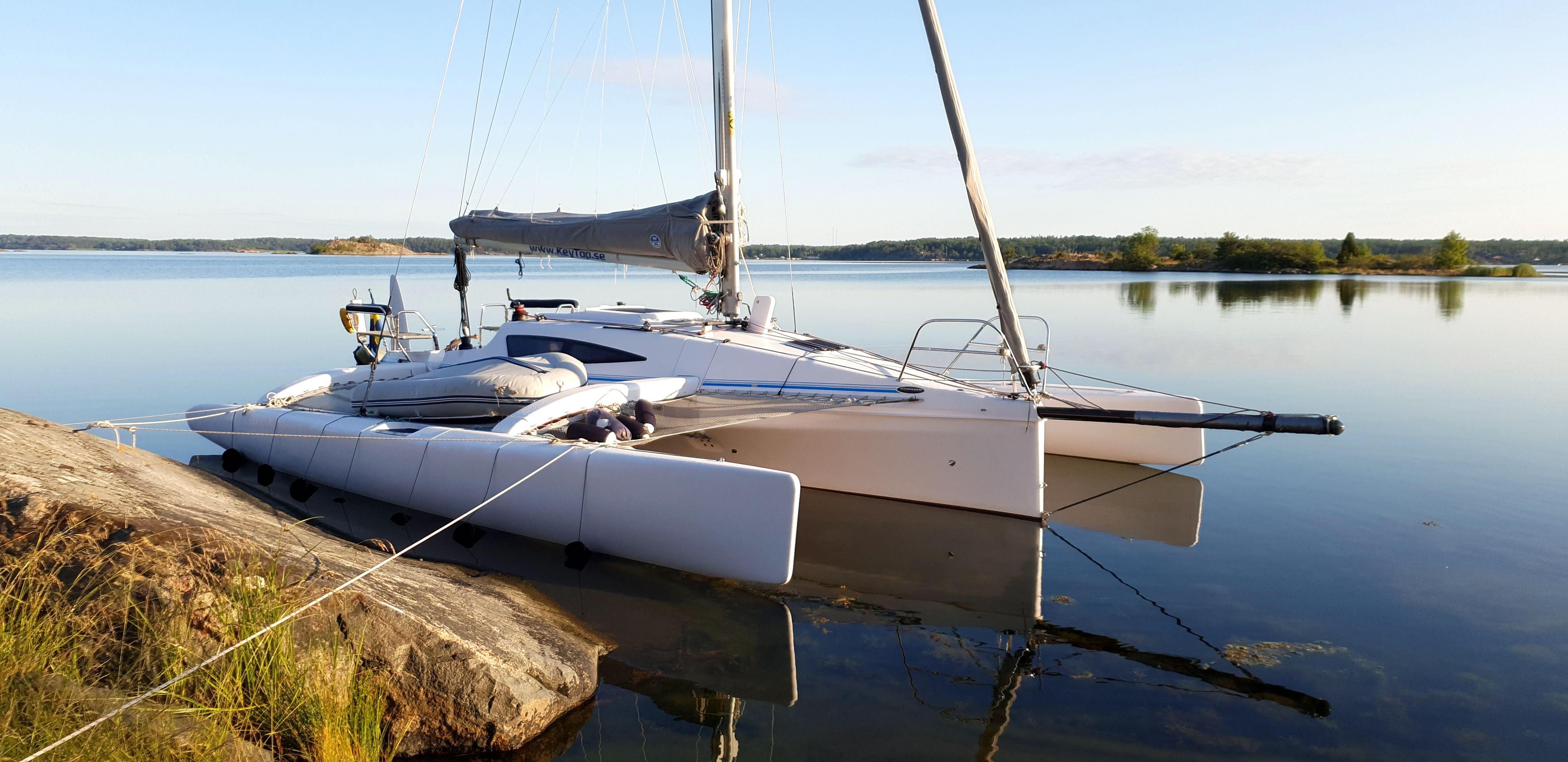 Corsair Cruze 970 XL trimaran moored on calm lake, 2015 model.