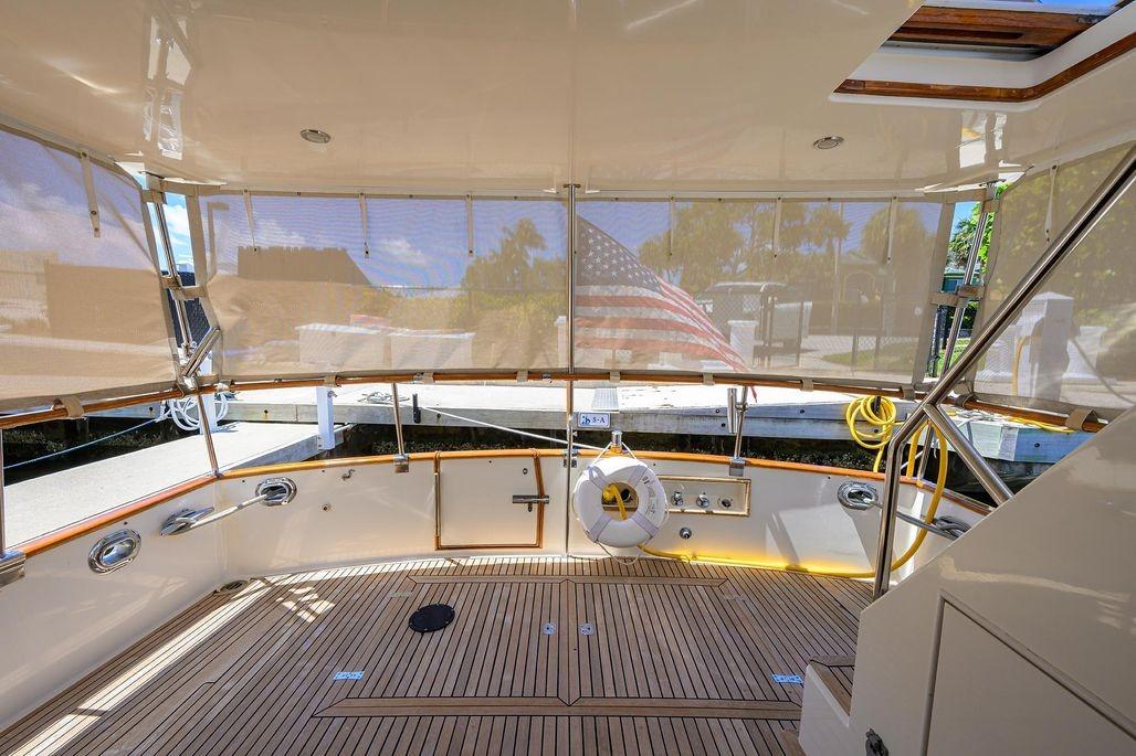 Spacious deck of 1999 Grand Banks 42 Europa yacht with American flag and wooden flooring.