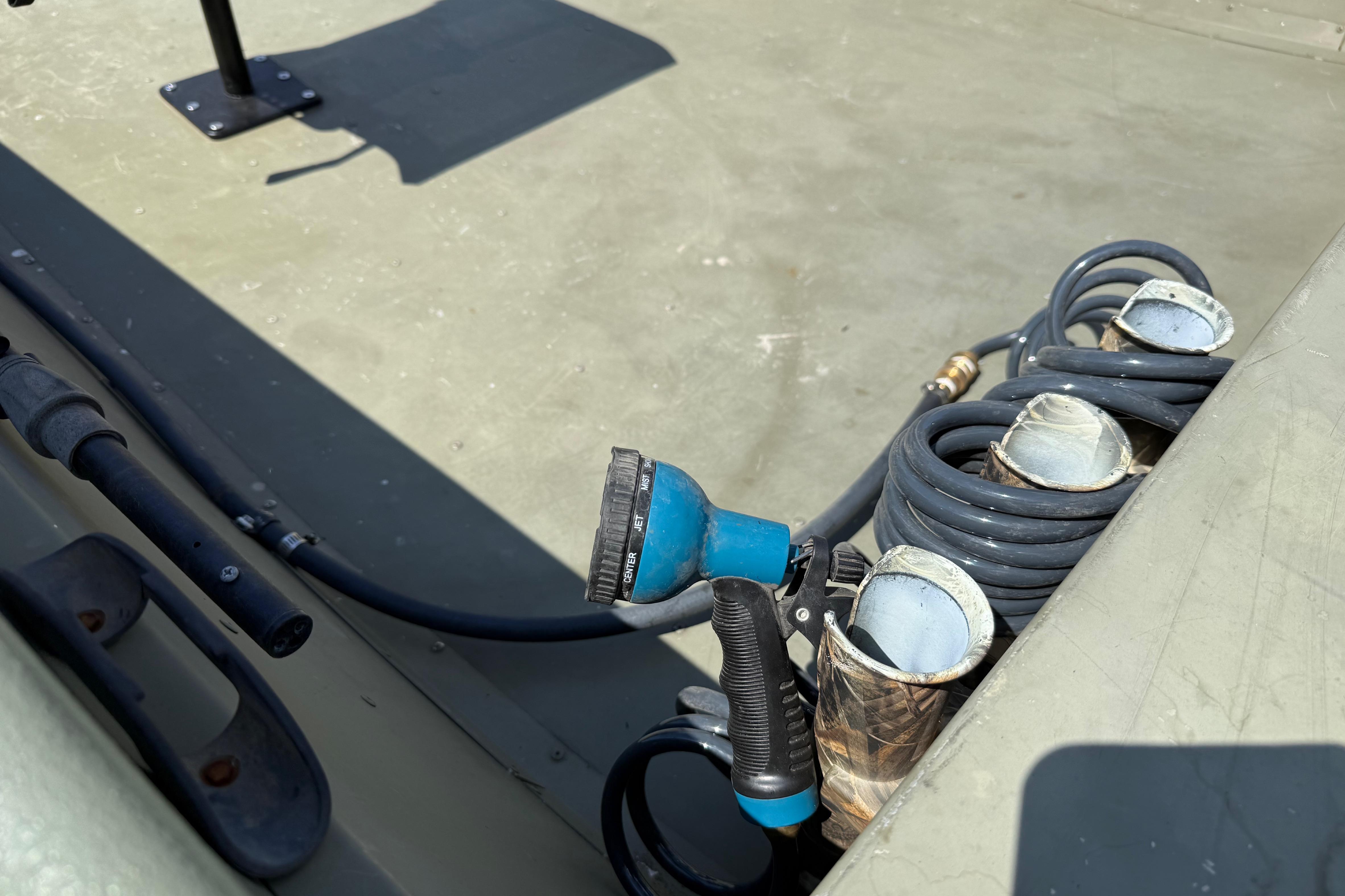 Close-up of a boat deck with hoses and a blue spray nozzle.