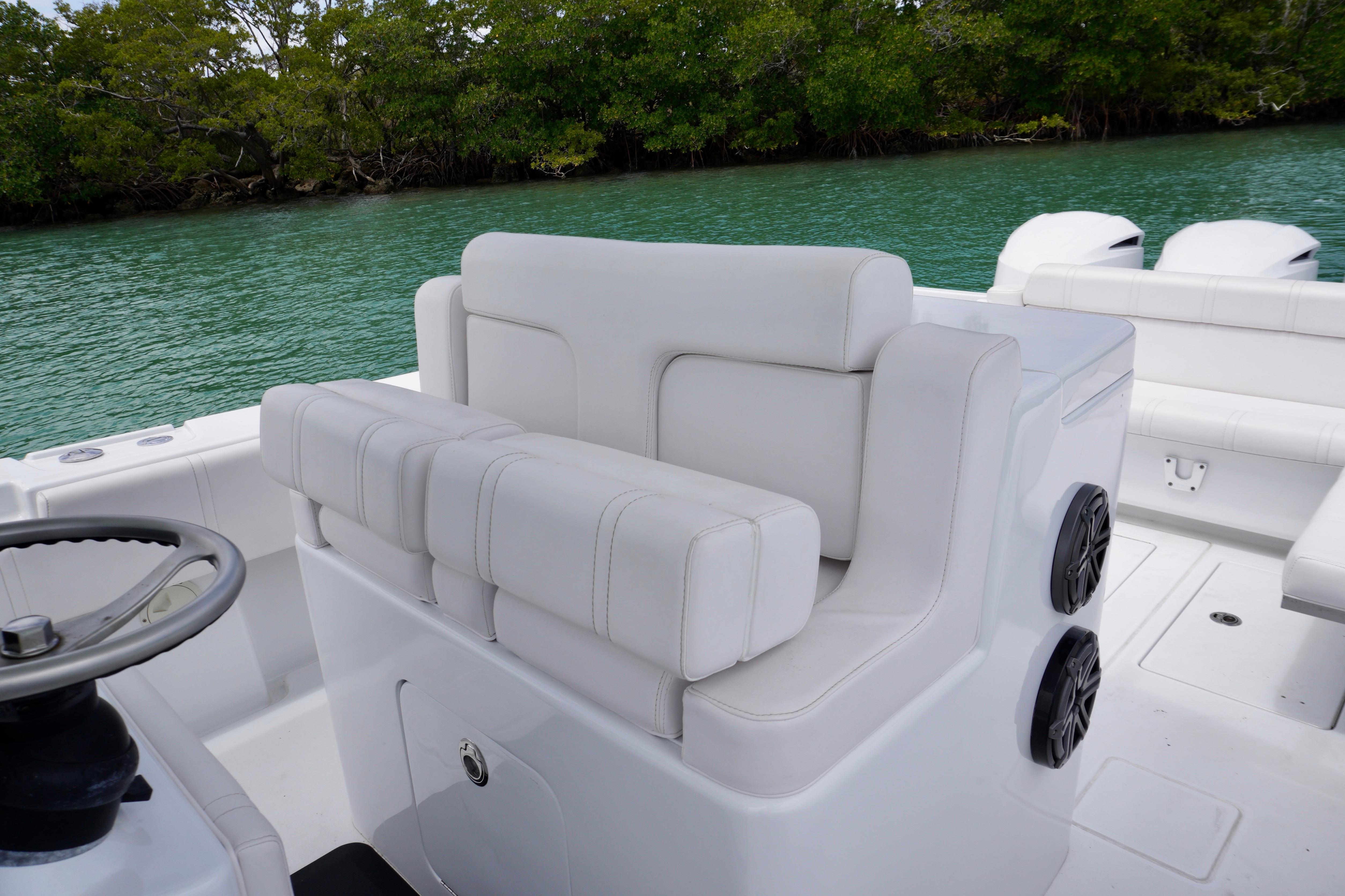 2013 Contender 35 LS boat interior with white seating and steering wheel, near lush greenery.