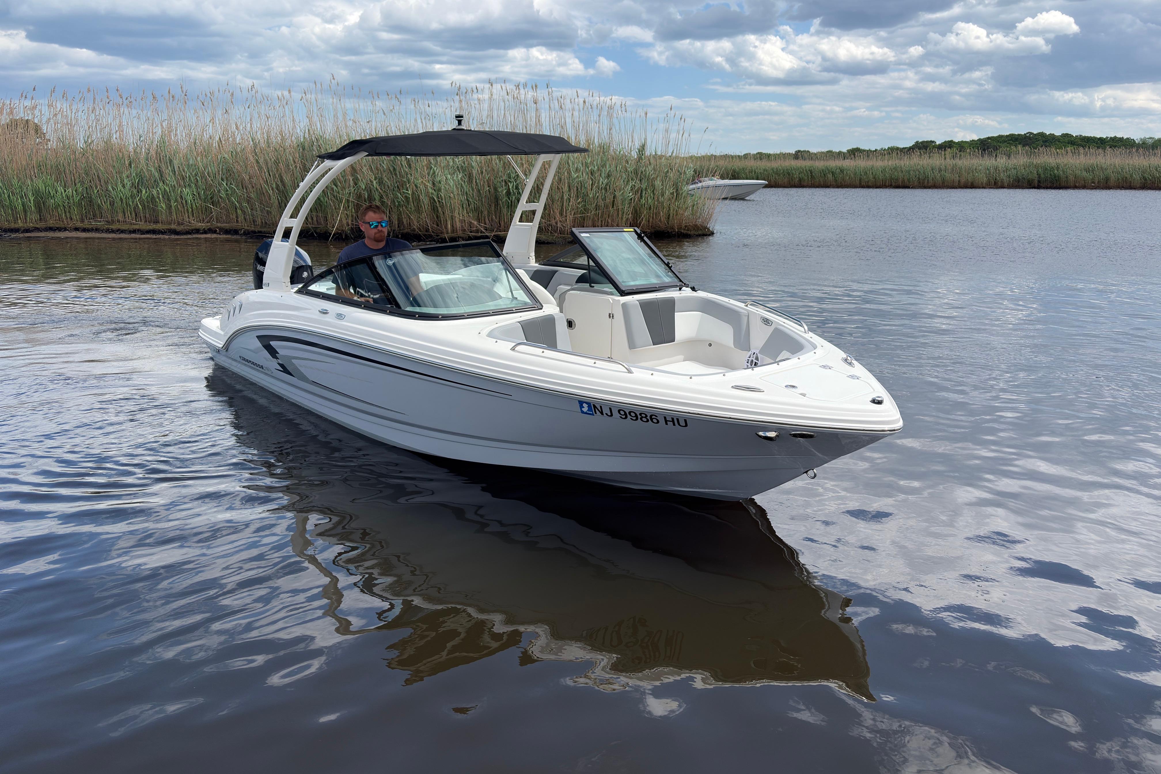 2026 Chaparral 23 SSi OB boat cruising on a calm lake under a cloudy sky.