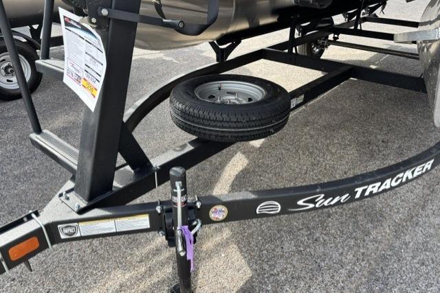 2026 Sun Tracker Party Barge 16 DLX trailer with spare tire on asphalt surface.