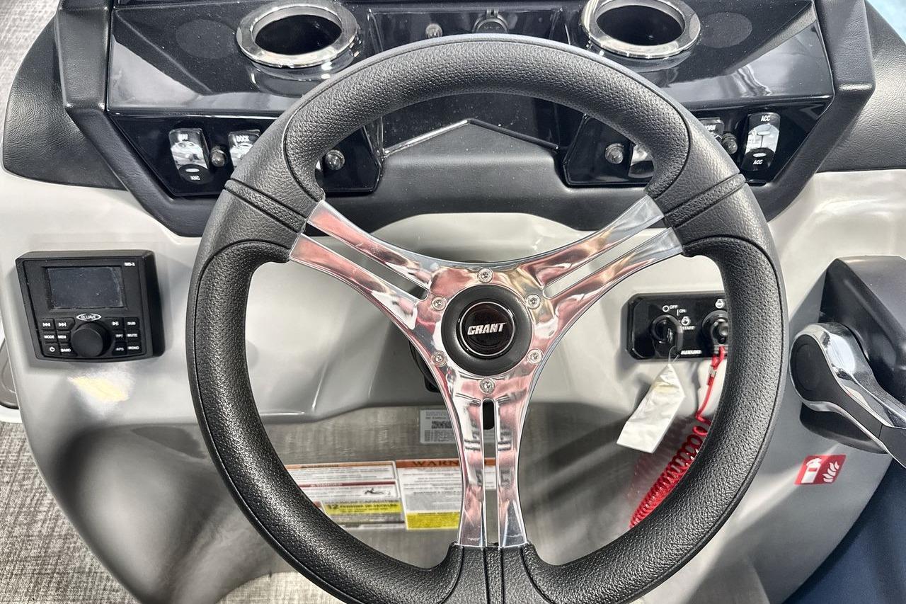 Steering wheel of 2026 Landau Island Breeze 23F boat with control panel and cup holders.