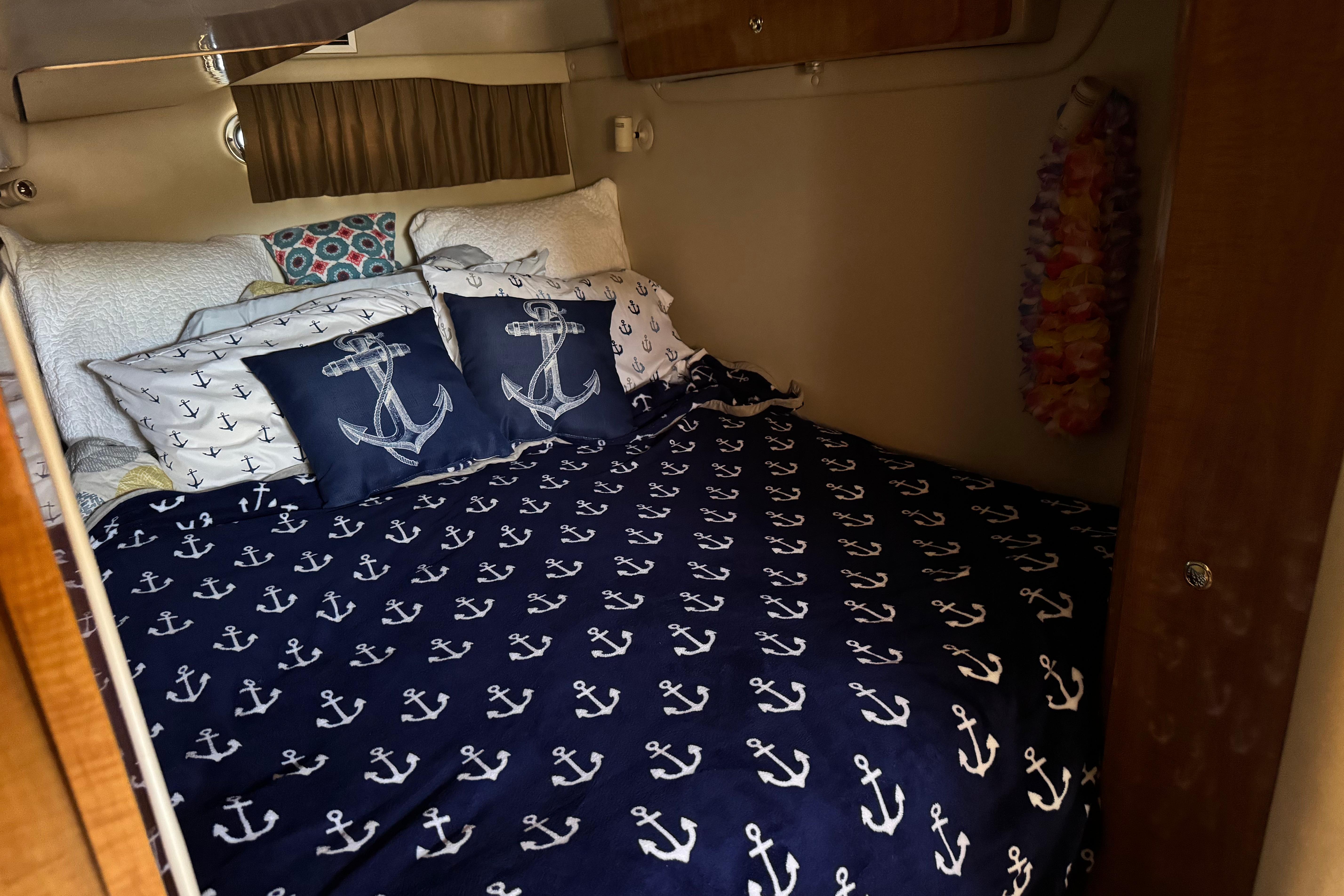 Cozy cabin bedroom in 2007 Regal Commodore 3860 with nautical-themed bedding.