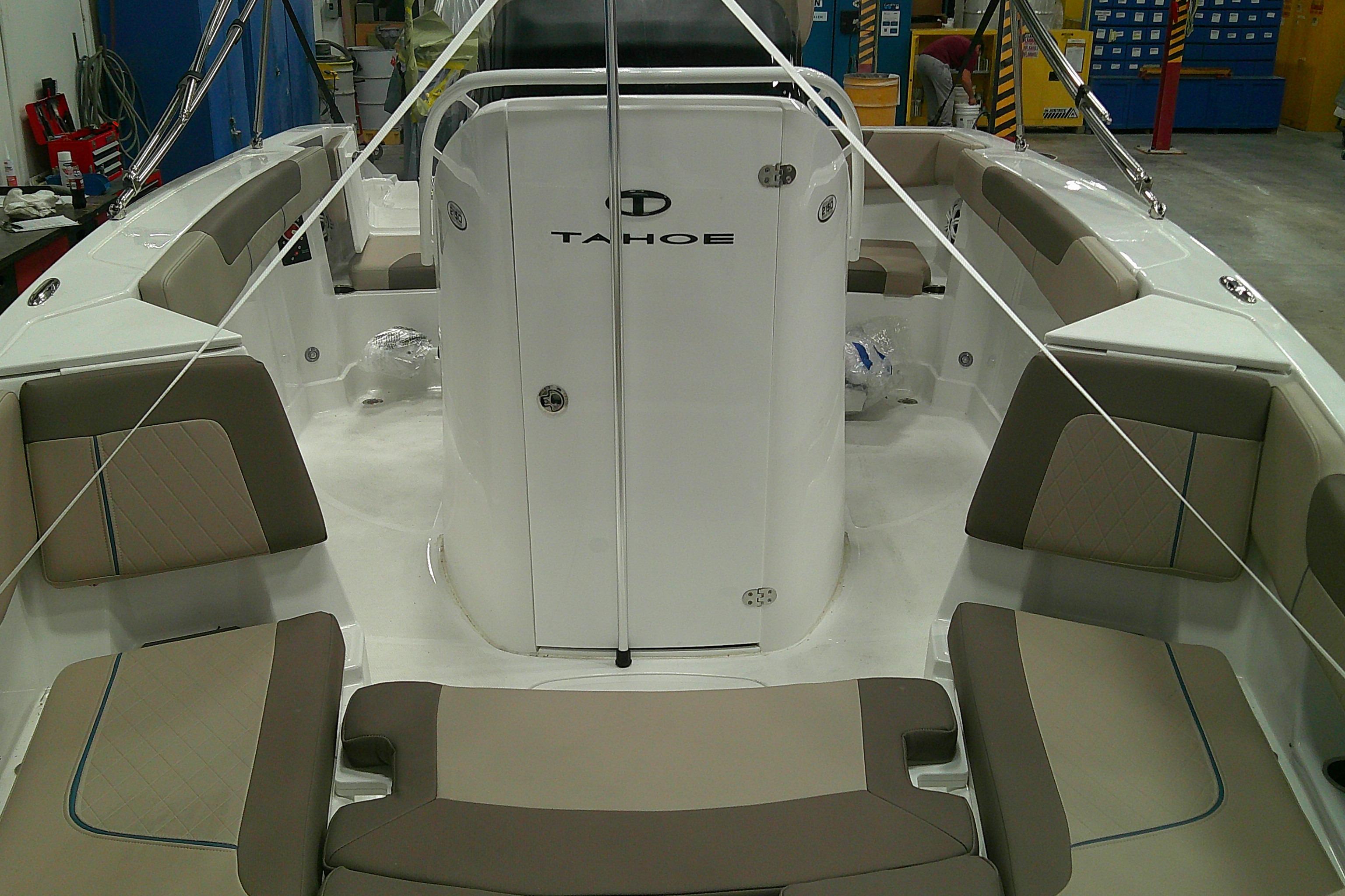 2026 Tahoe 2150 CC boat interior with beige seating and white console in a workshop.