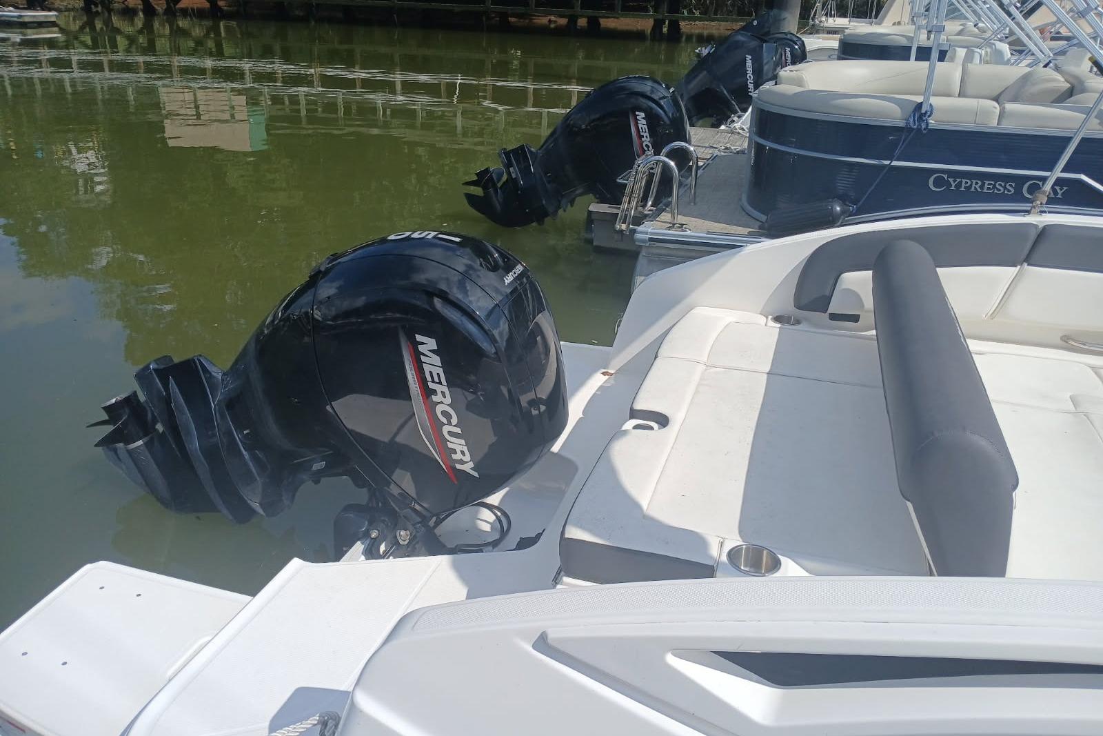 2023 Bayliner DX 2200 with Mercury outboard motor docked on calm water.