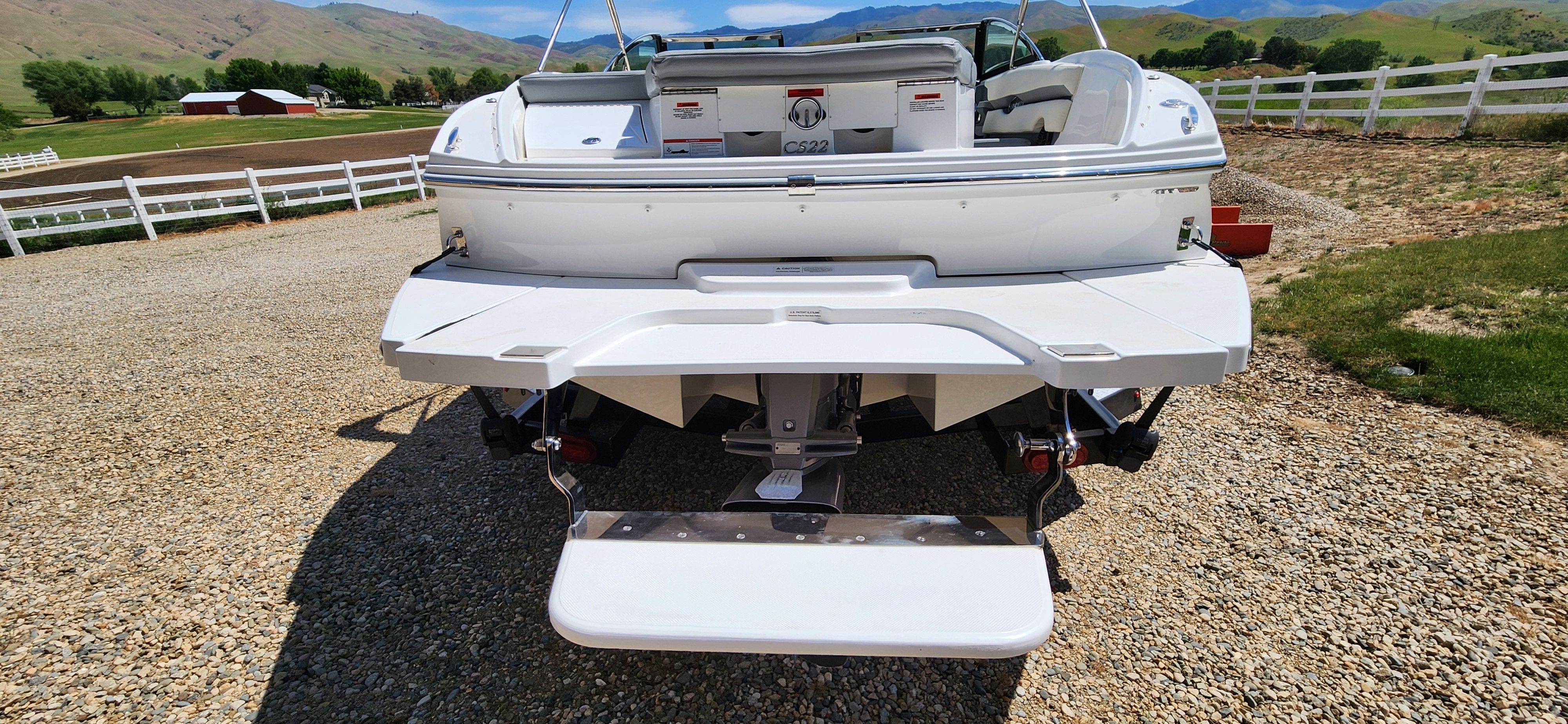 The boat is on a gravel path with mountains in the background.