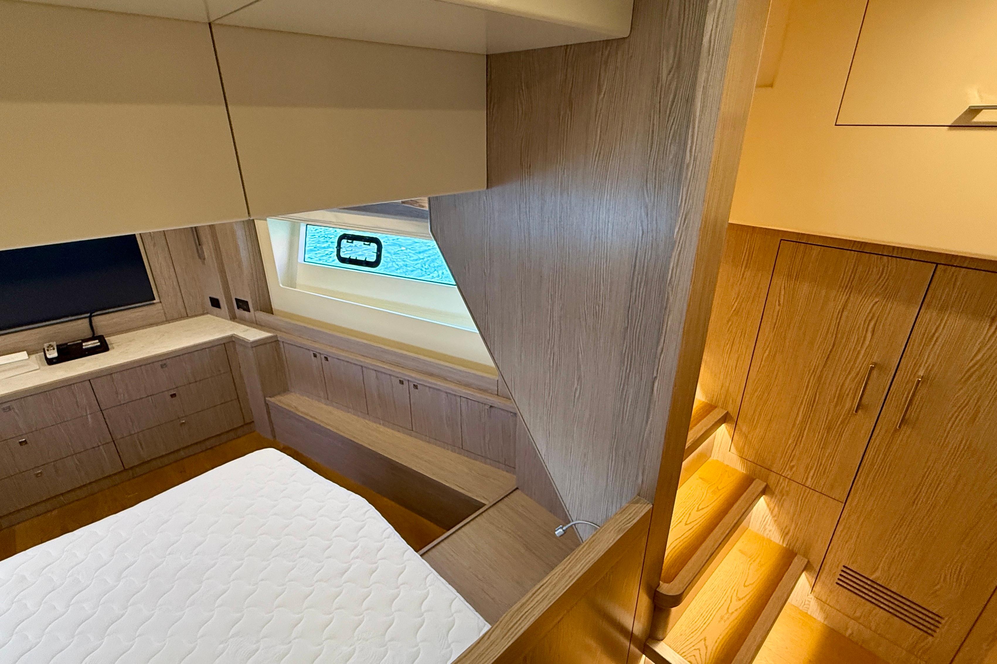 Luxurious interior of 2022 Sirena 58 yacht with wooden cabinetry and cozy bedding.