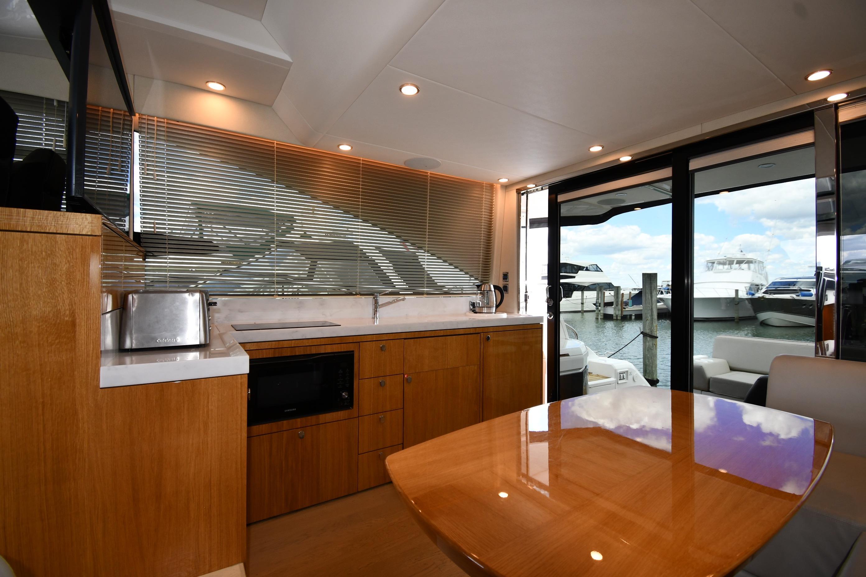 Luxurious interior of 2024 Fairline G50 Targa yacht with modern kitchen and marina view.