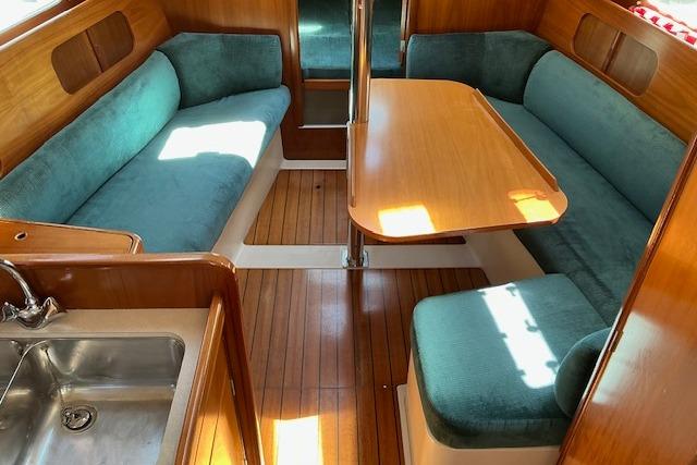 Interior of 2000 Beneteau Oceanis 321 sailboat with wood finish and teal seating.