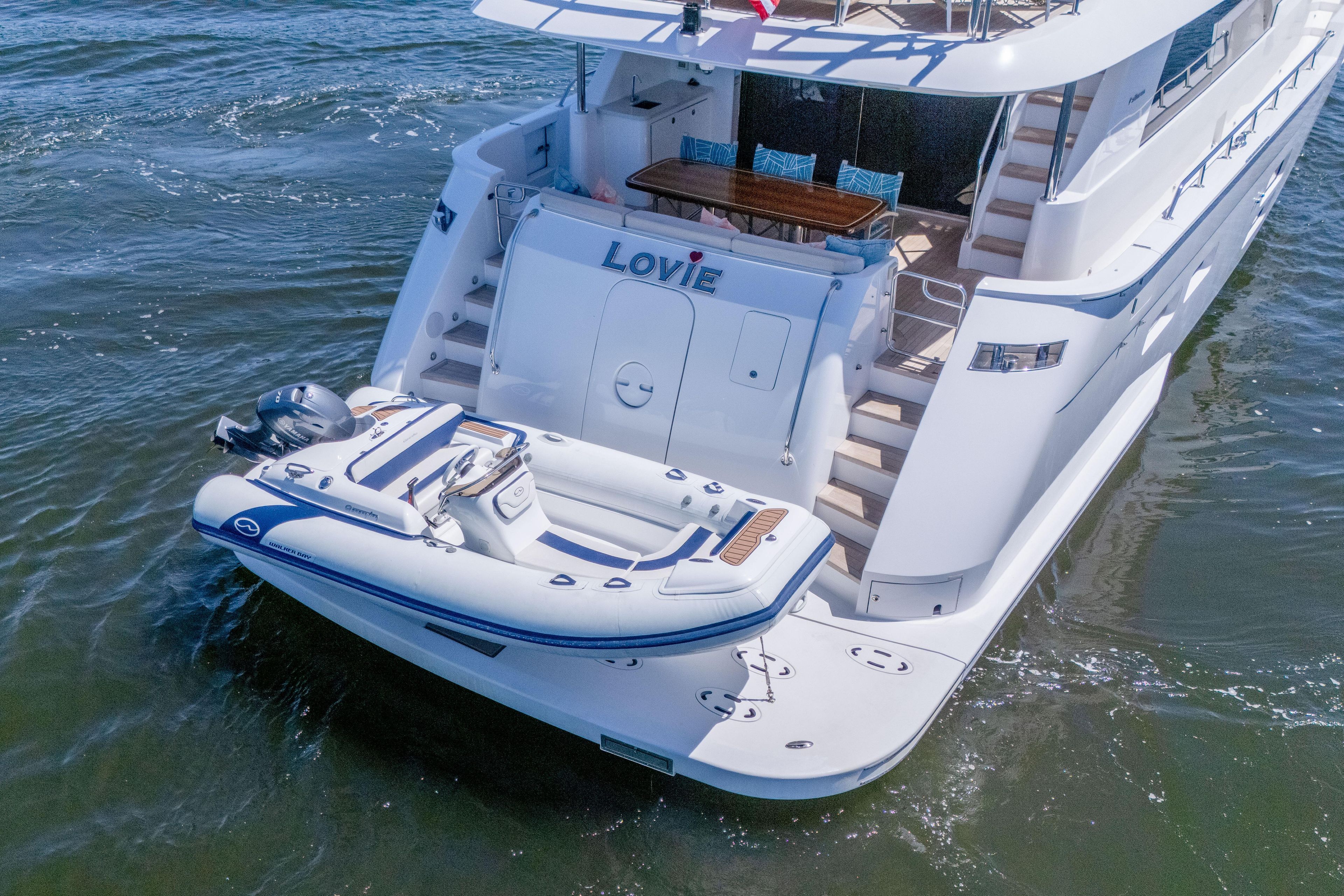 2021 Hatteras M75 Panacera yacht with tender on water, rear view.