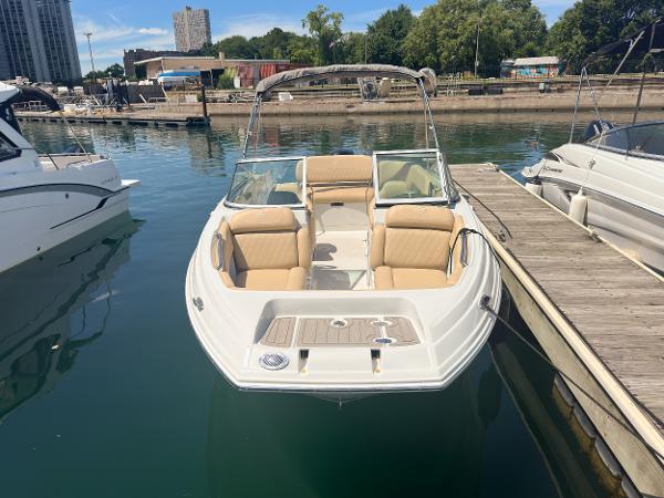 2023 Crownline 215 XS boat docked in a marina, featuring beige seating and sleek design.
