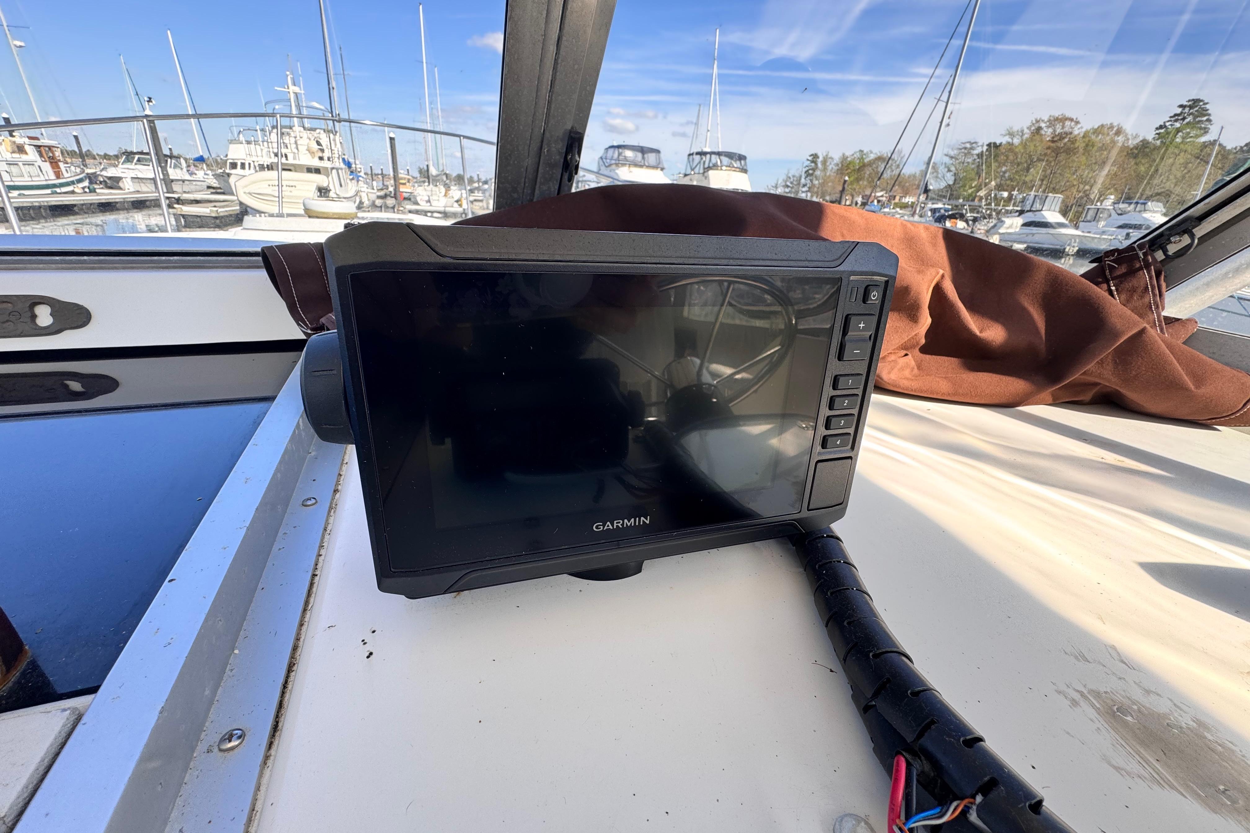 Garmin device on 1987 Luhrs Alura 30 boat, docked in marina under clear sky.