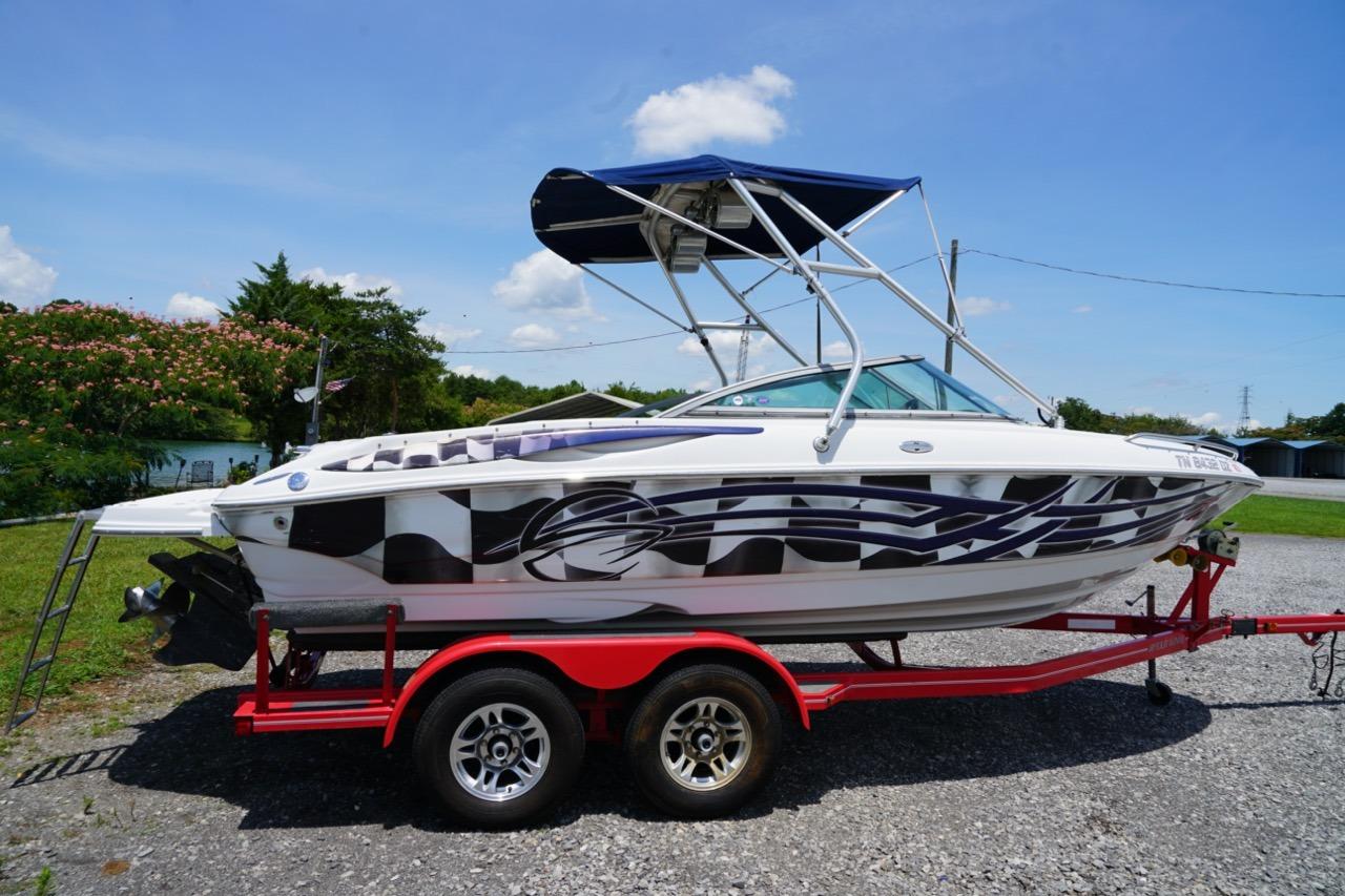 2004 Crownline 216 LS boat on red trailer with custom graphics and canopy.