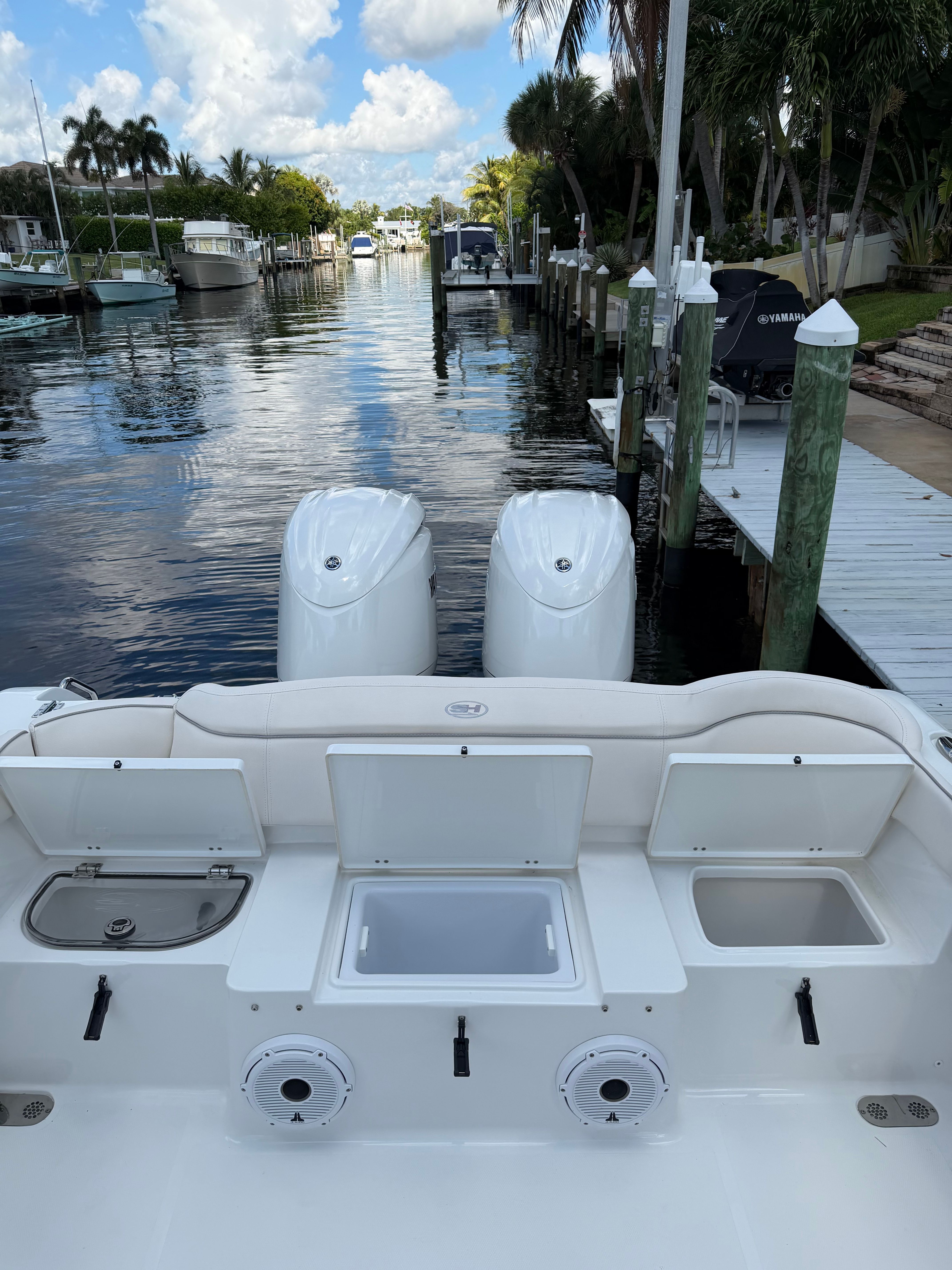 The image shows the stern of a Sea Hunt Ultra 265 SE boat with twin engines, docked in a calm marina.