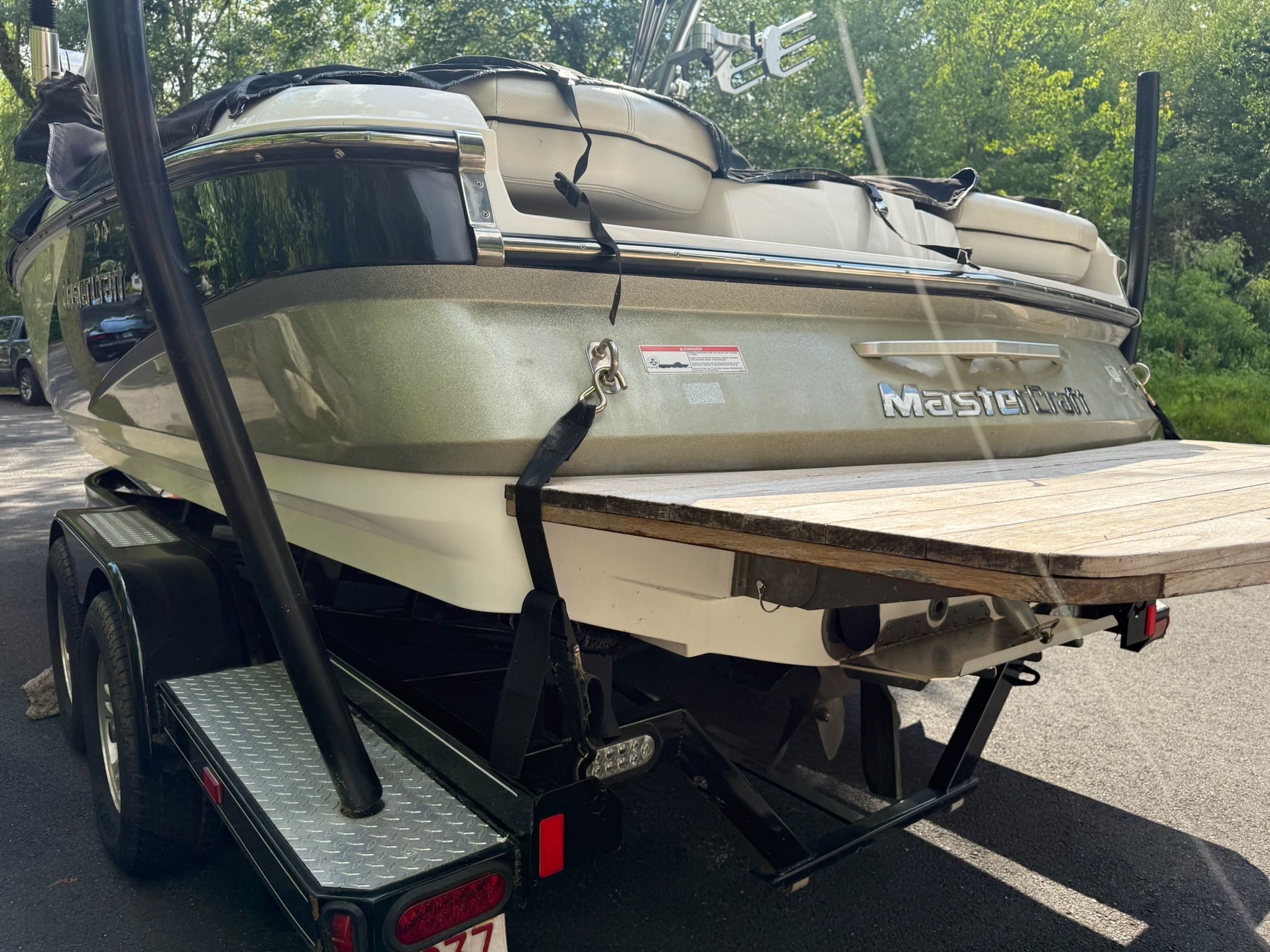 Rear view of a MasterCraft X-25 boat on a trailer, surrounded by trees.