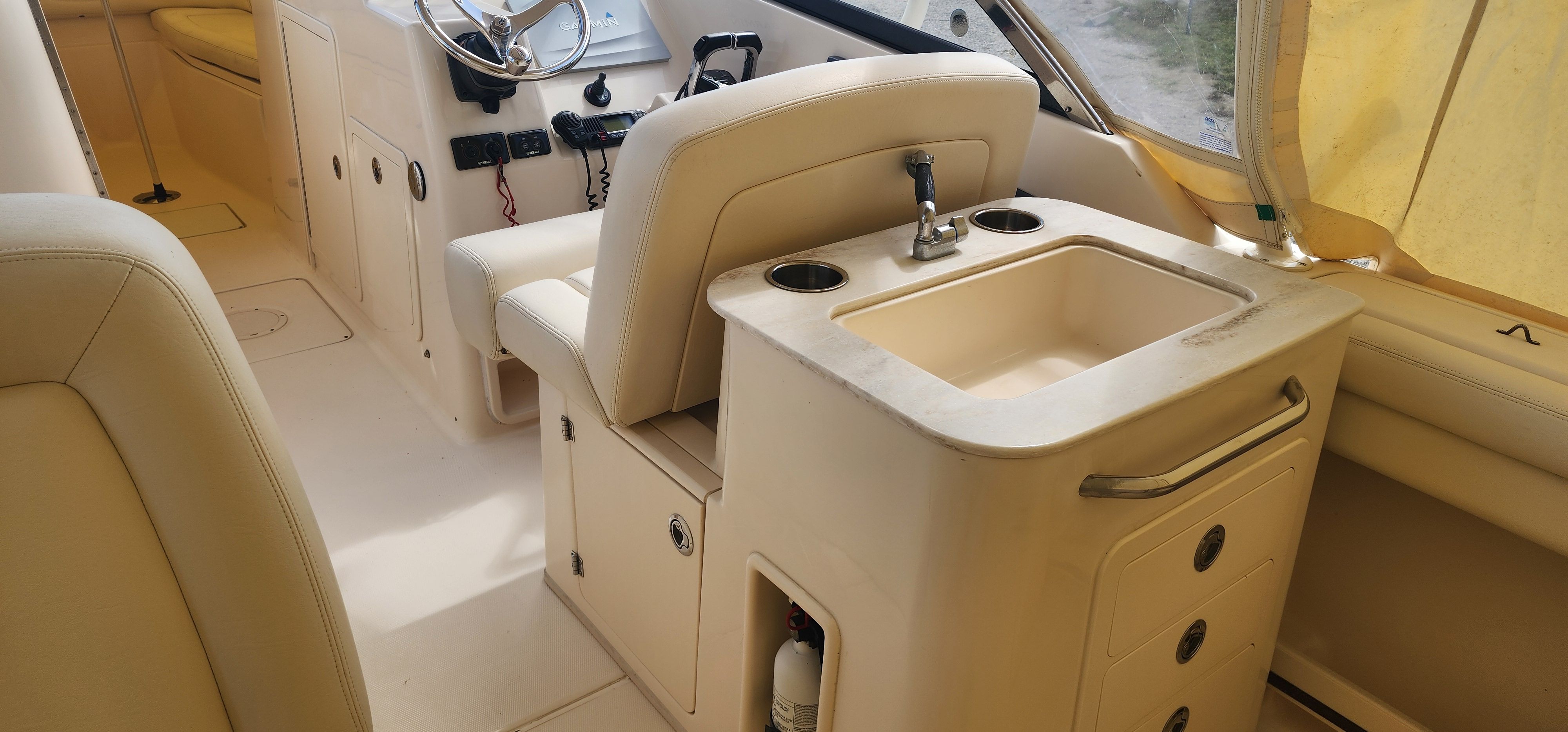 The image shows the cockpit of a 2015 Grady-White Freedom 275 with beige seats and a sink.