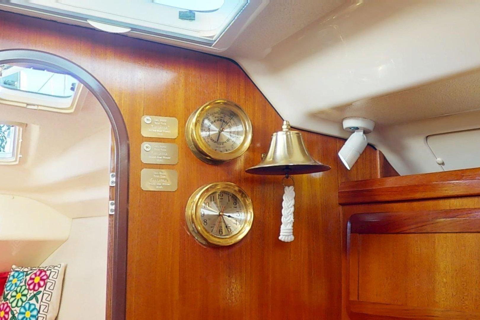 Interior of 1997 Hunter Legend 40.5 yacht with brass instruments and bell on wooden panel.