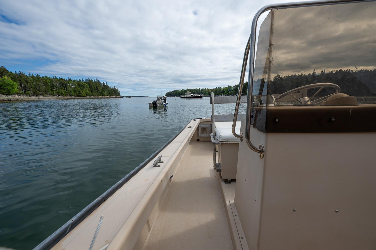 1989 Ellis 24 Open boat cruising on a calm lake with forested shoreline.