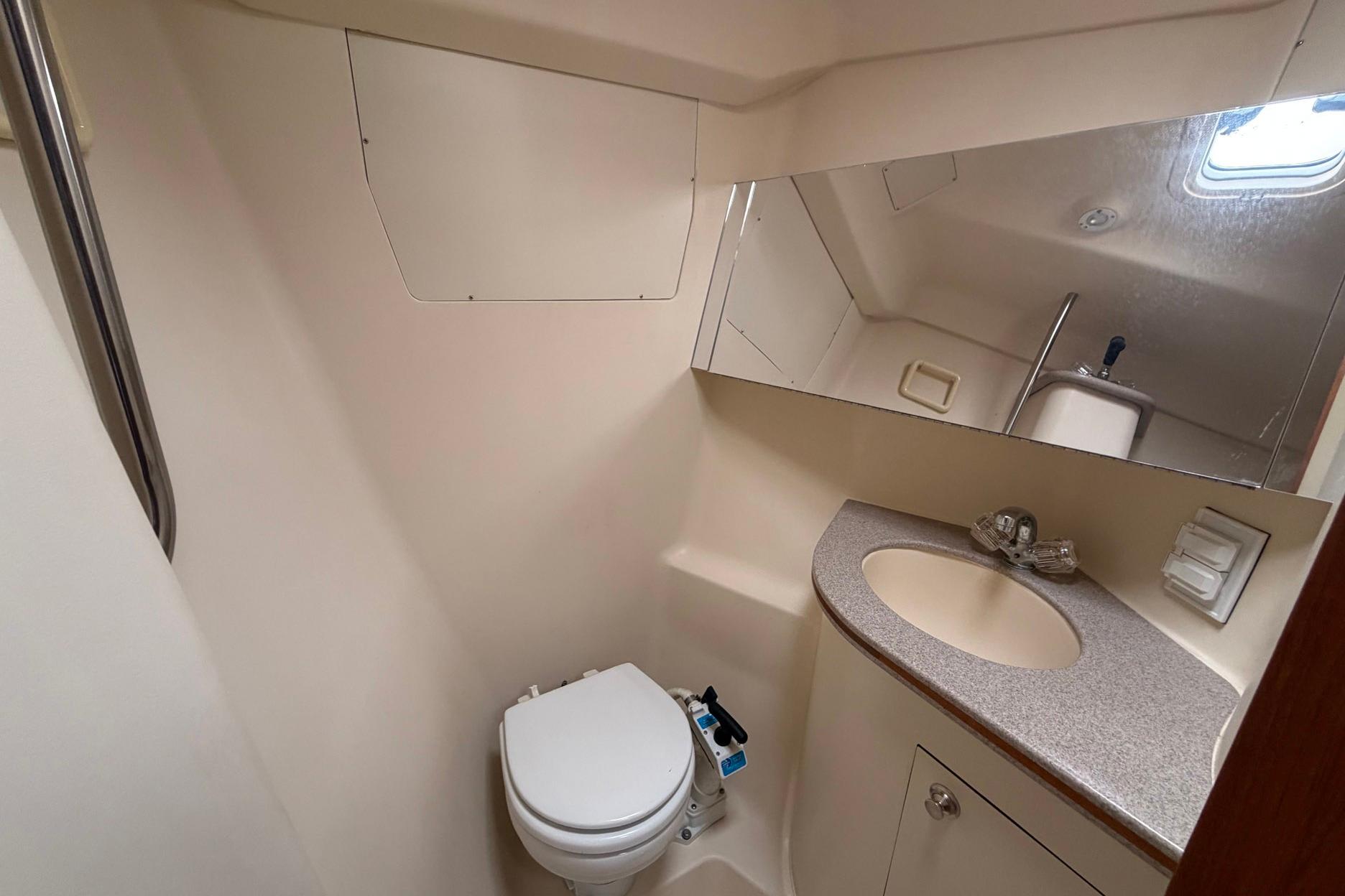 Compact bathroom in a 1998 Hunter 410 yacht with toilet, sink, and mirror.