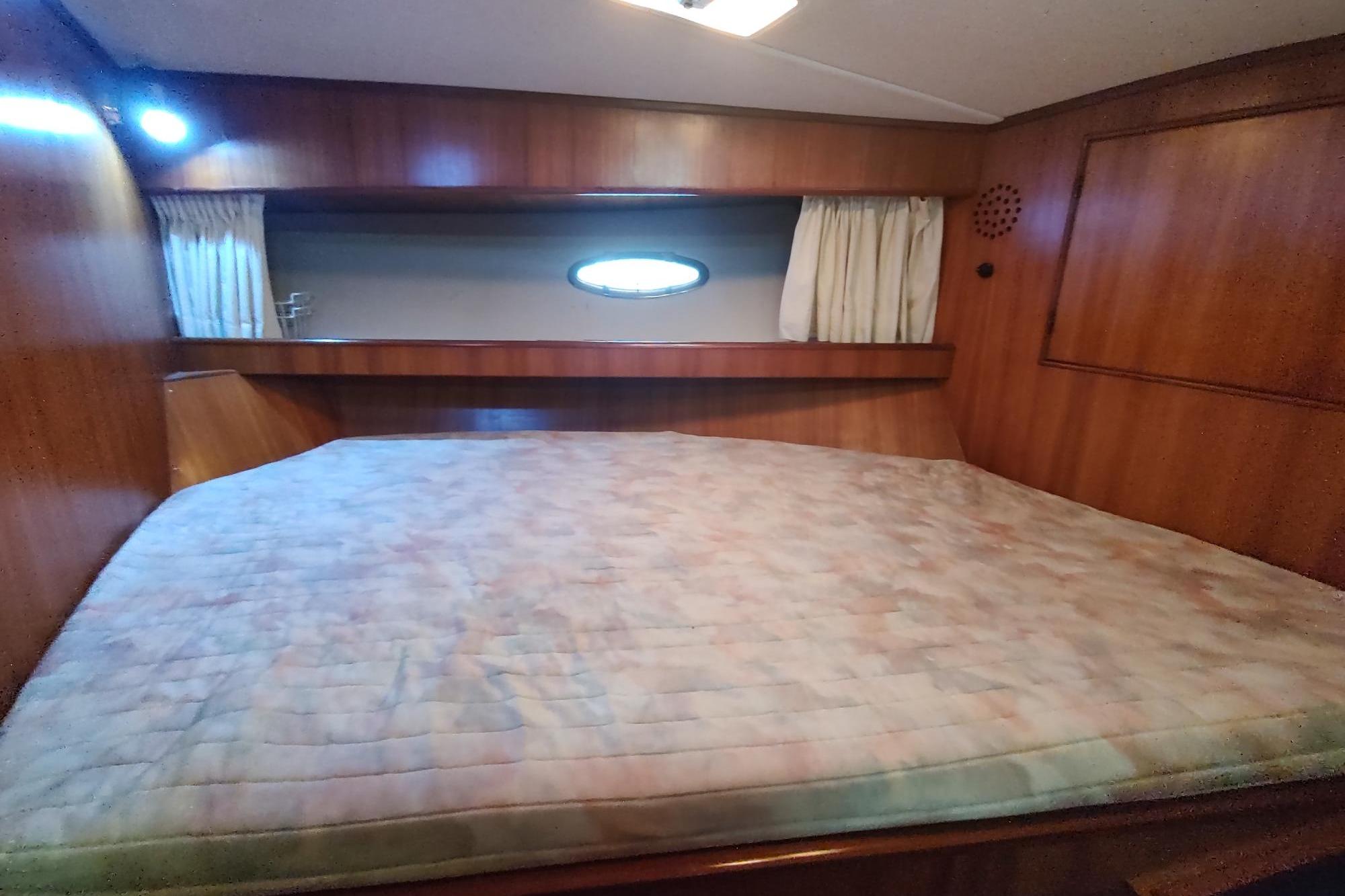1989 Hyatt Double Cabin Motoryacht bedroom with wood paneling and large bed.