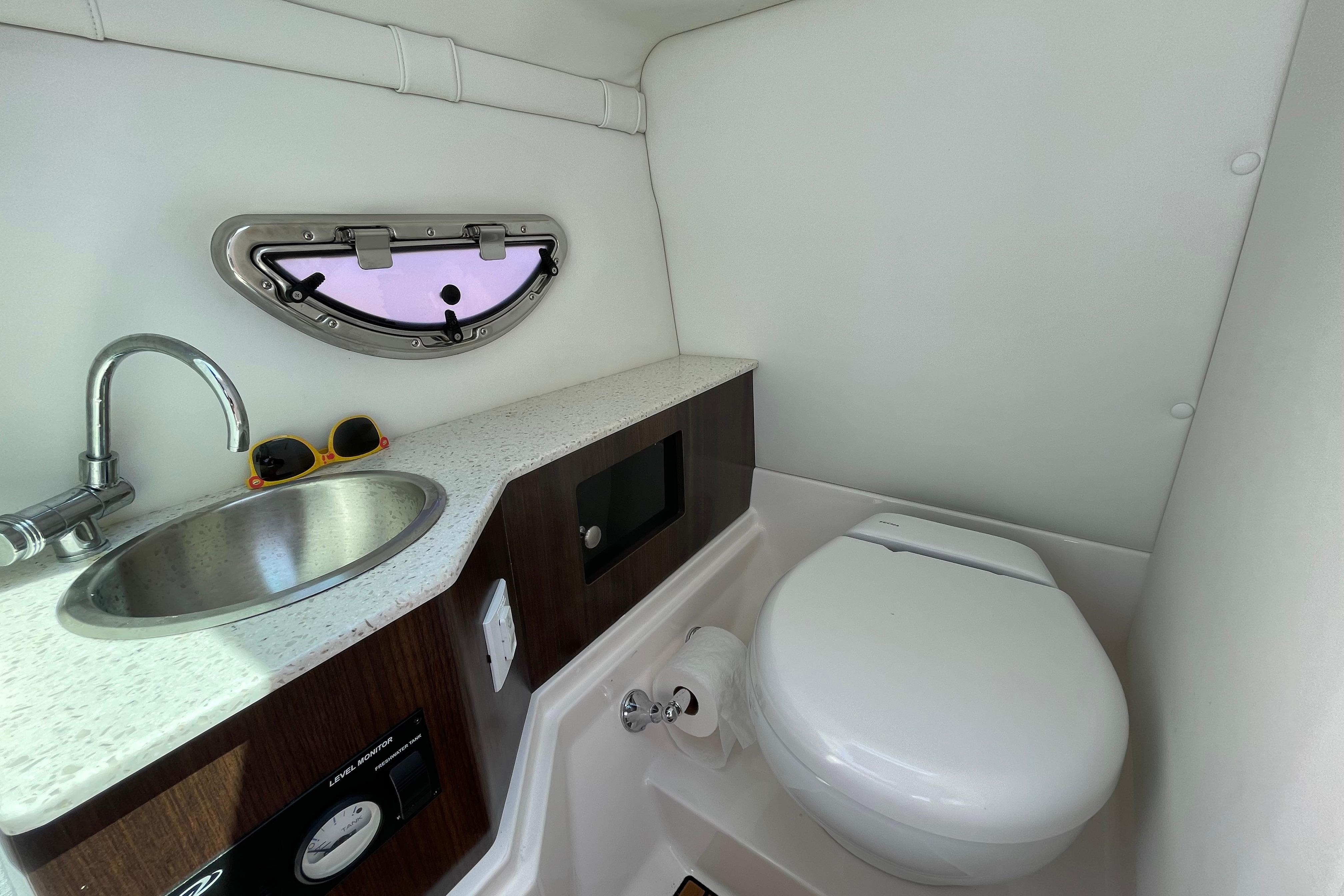 2018 Regal 26 OBX boat bathroom with sink, toilet, and porthole window.