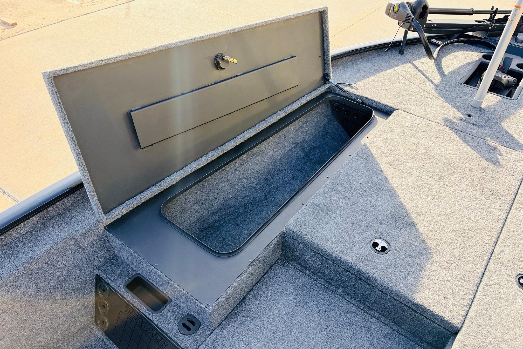 Open storage compartment in 2025 Tracker Savage 215 boat, featuring carpeted interior.