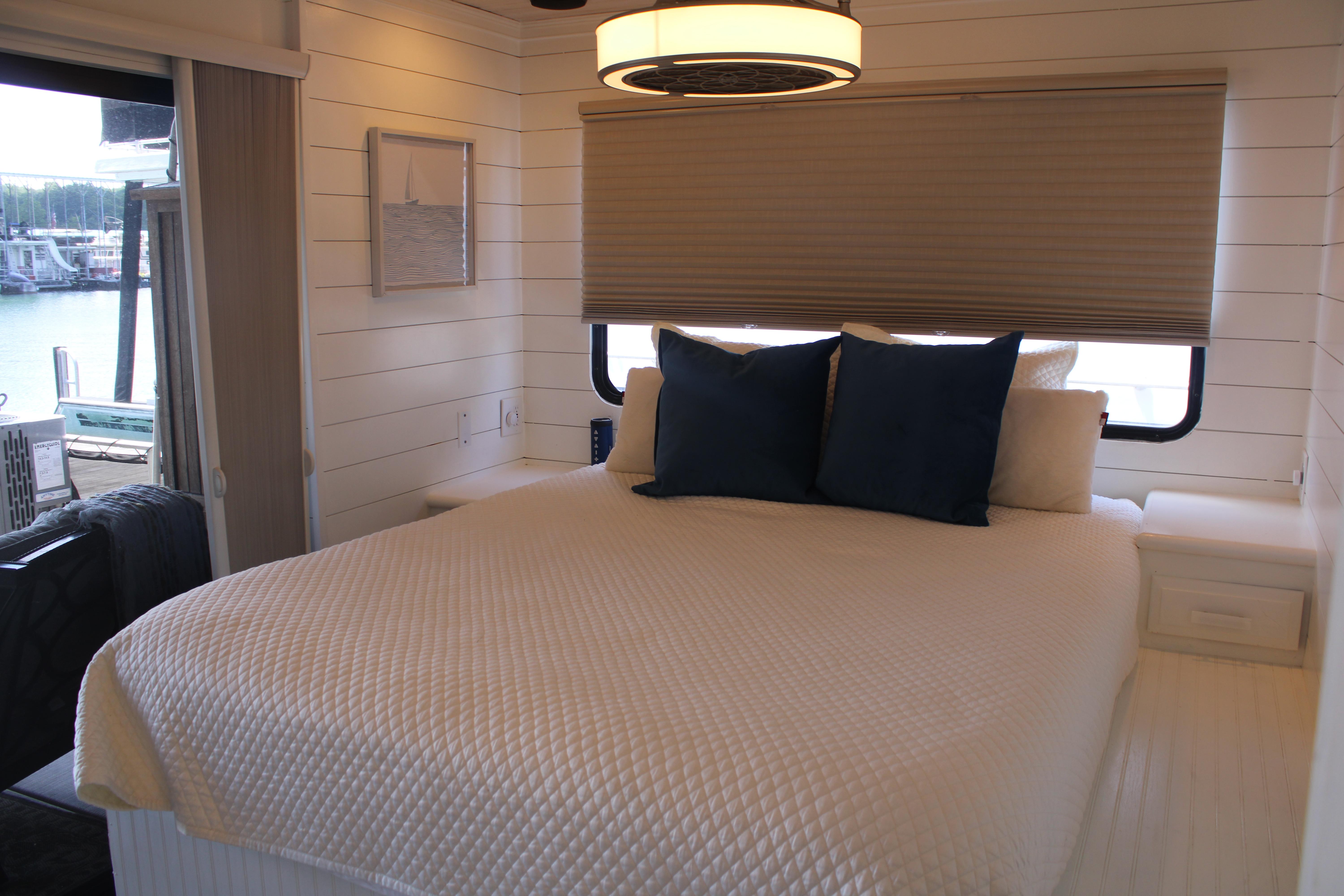 Cozy bedroom interior on 1992 Sumerset 66 houseboat with white bedding and blue pillows.