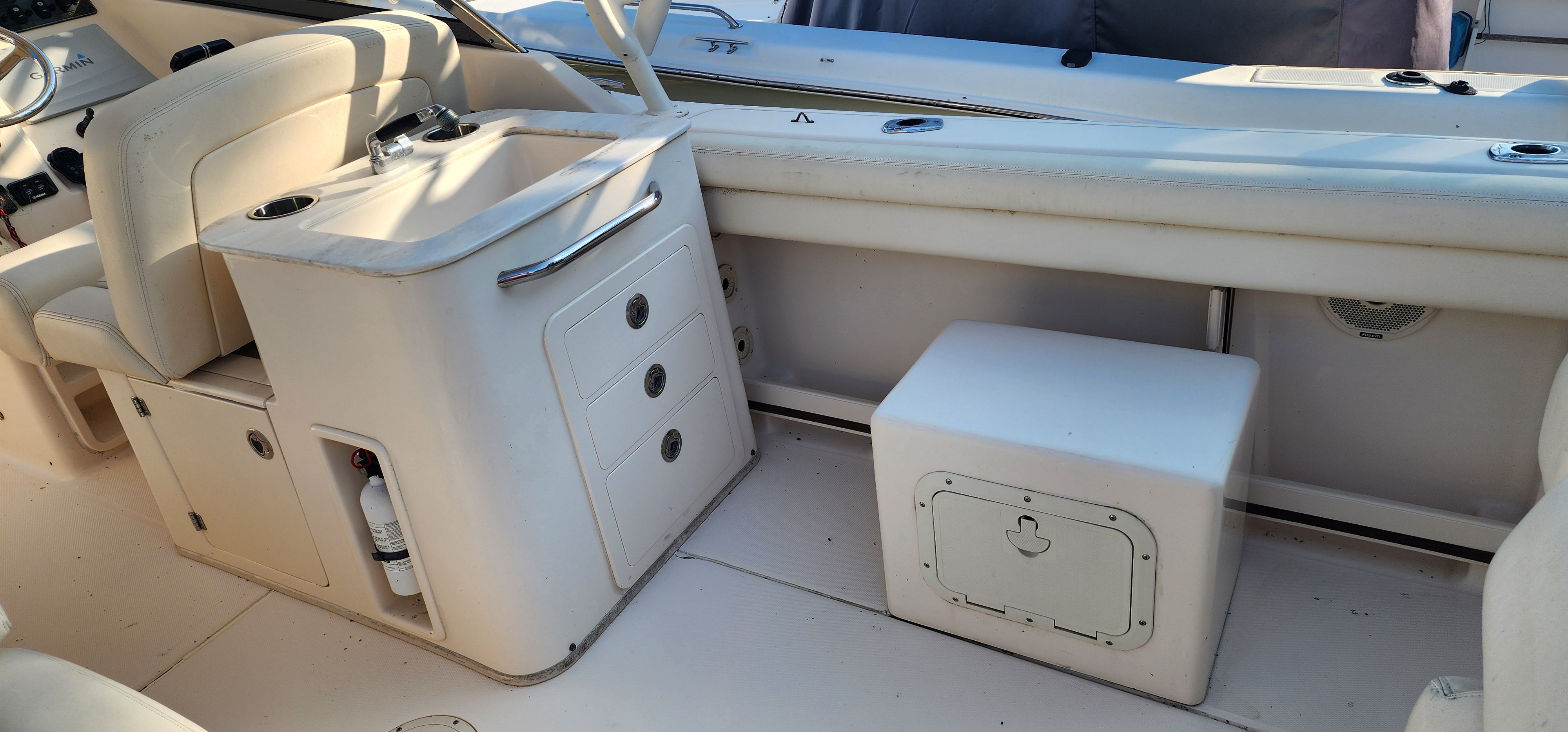 The image shows the cockpit of a 2015 Grady-White Freedom 275. There's a seating area, sink, and storage with drawers.